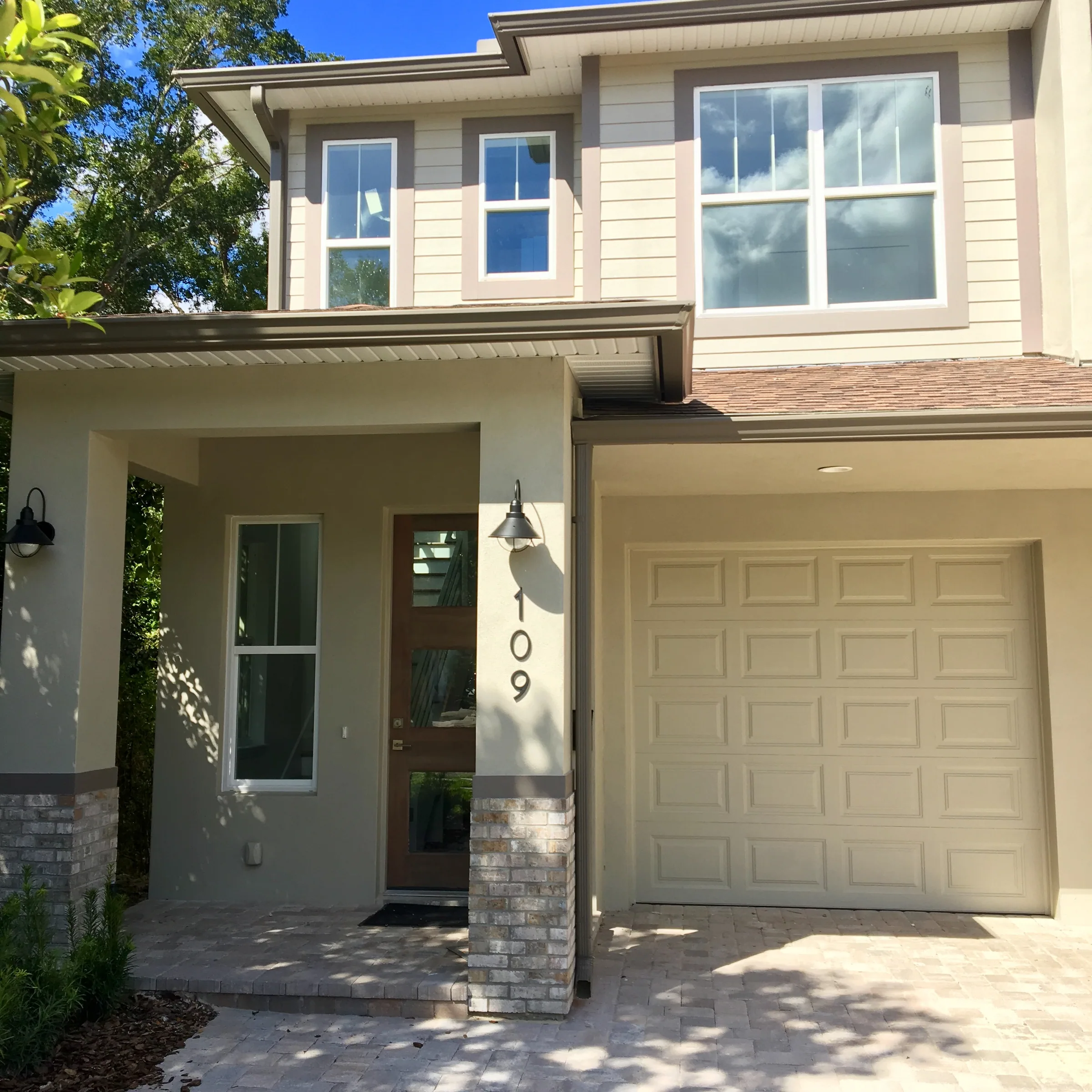 Covered entry marked 109 beside a garage, with brick-faced column bases and a two-story siding facade.