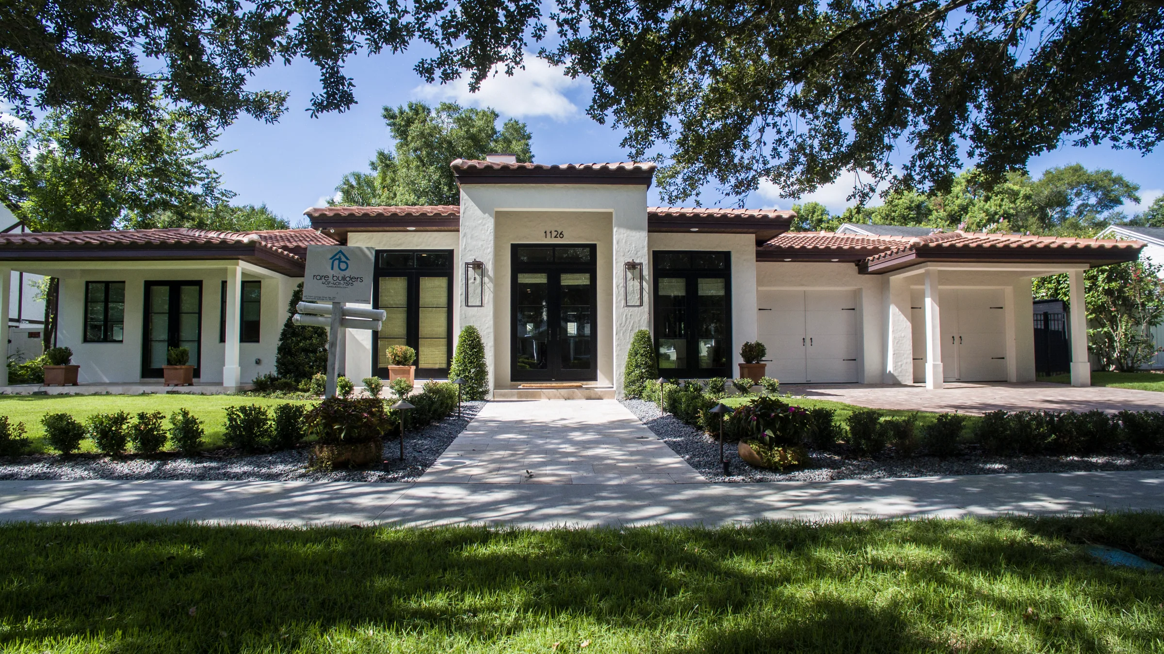 White Reading residence with a low tiled roof, dark-framed windows, a central glazed entry and landscaped approach.