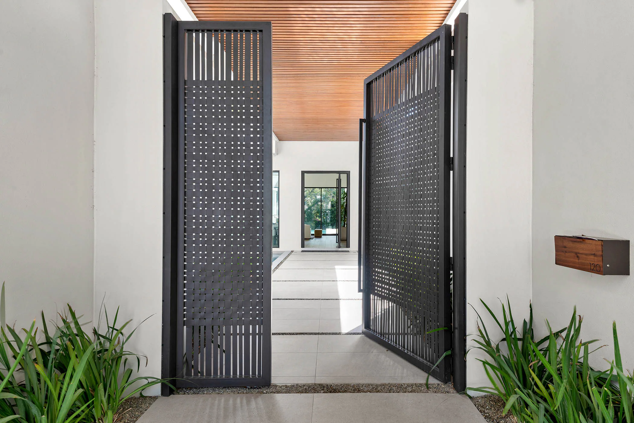 Dark perforated entry gate beneath a wood-lined canopy.