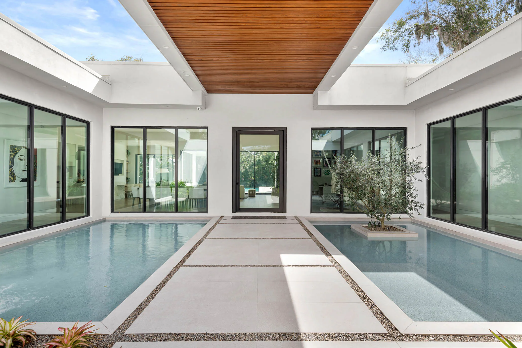 Linear courtyard pool between white wings and black-framed glazing. Spring, a custom home by Rare Builders in Orlando.