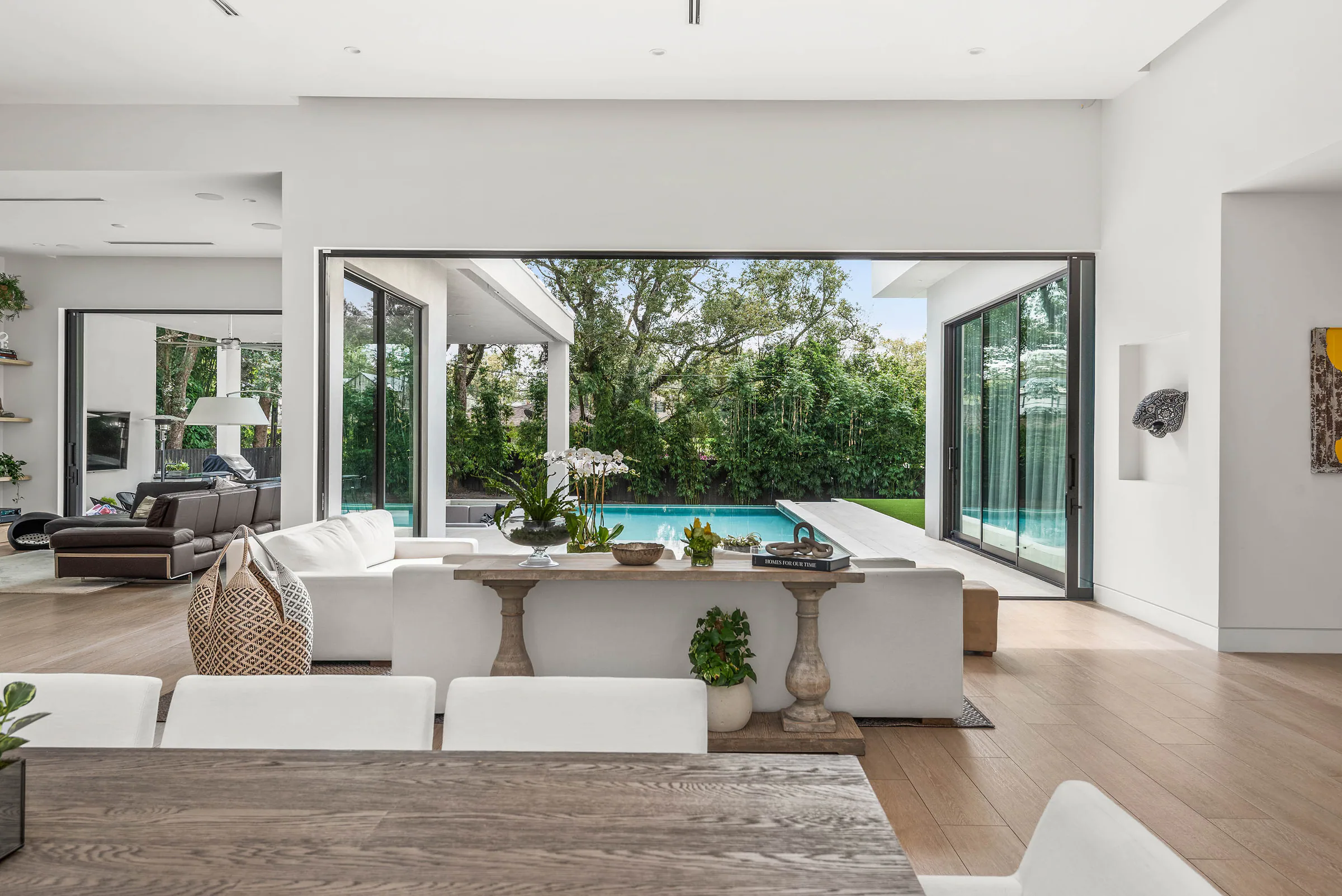Pale living room opening through glass to the pool. Spring, a custom home by Rare Builders in Orlando.