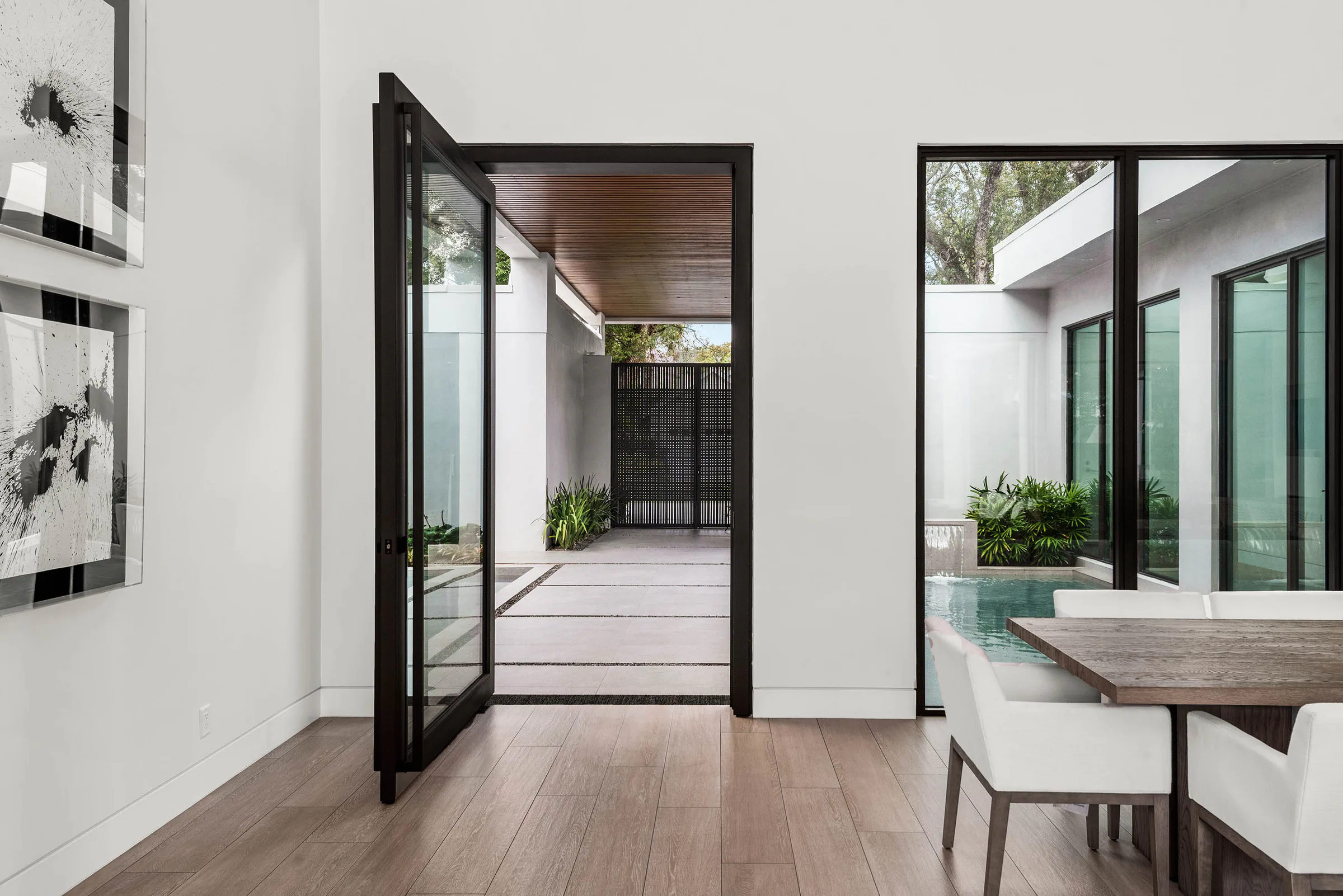 Black-framed pivot door beside the courtyard pool.