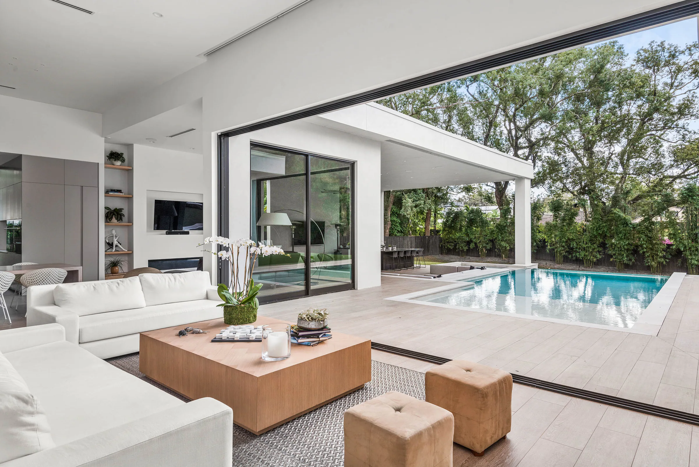 Living room with pale seating and full-height pool glazing.