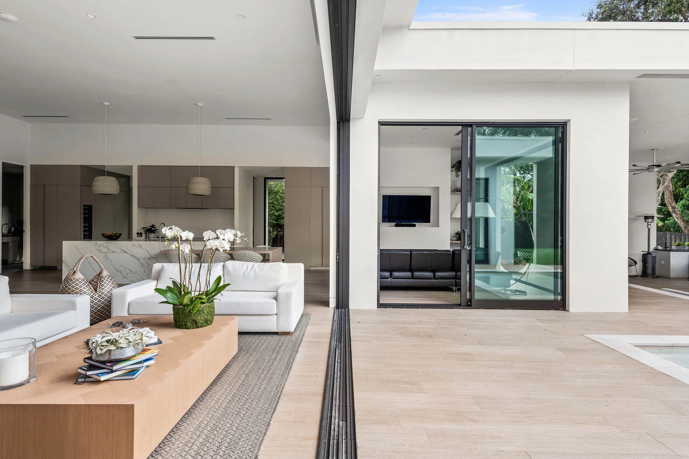 Low pale sofa with the courtyard pool beyond. Spring, a custom home by Rare Builders in Orlando.