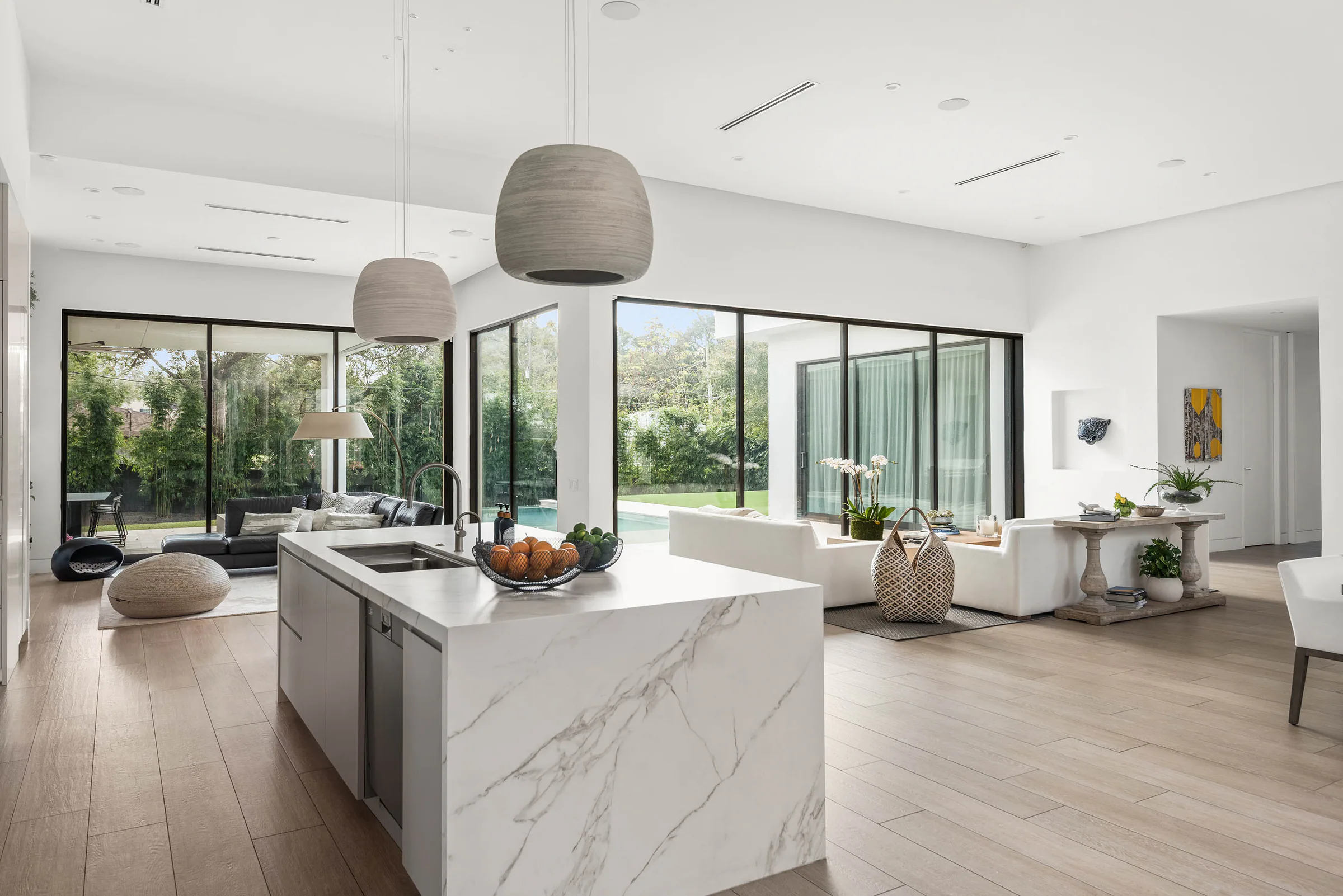 Marble waterfall island beneath rounded pendant lights.