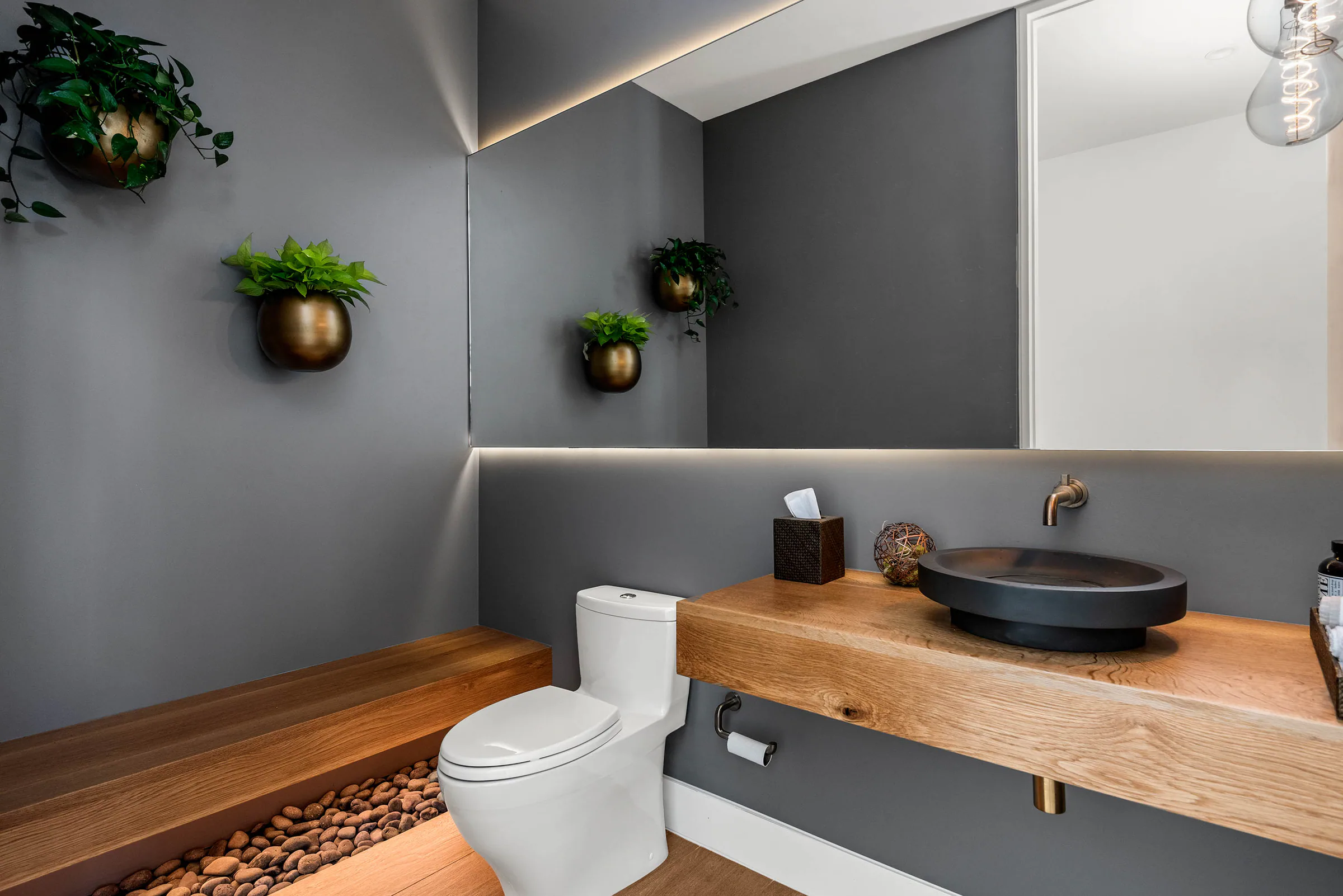 Dark grey bathroom wall with a floating wood vanity. Spring, a custom home by Rare Builders in Orlando.