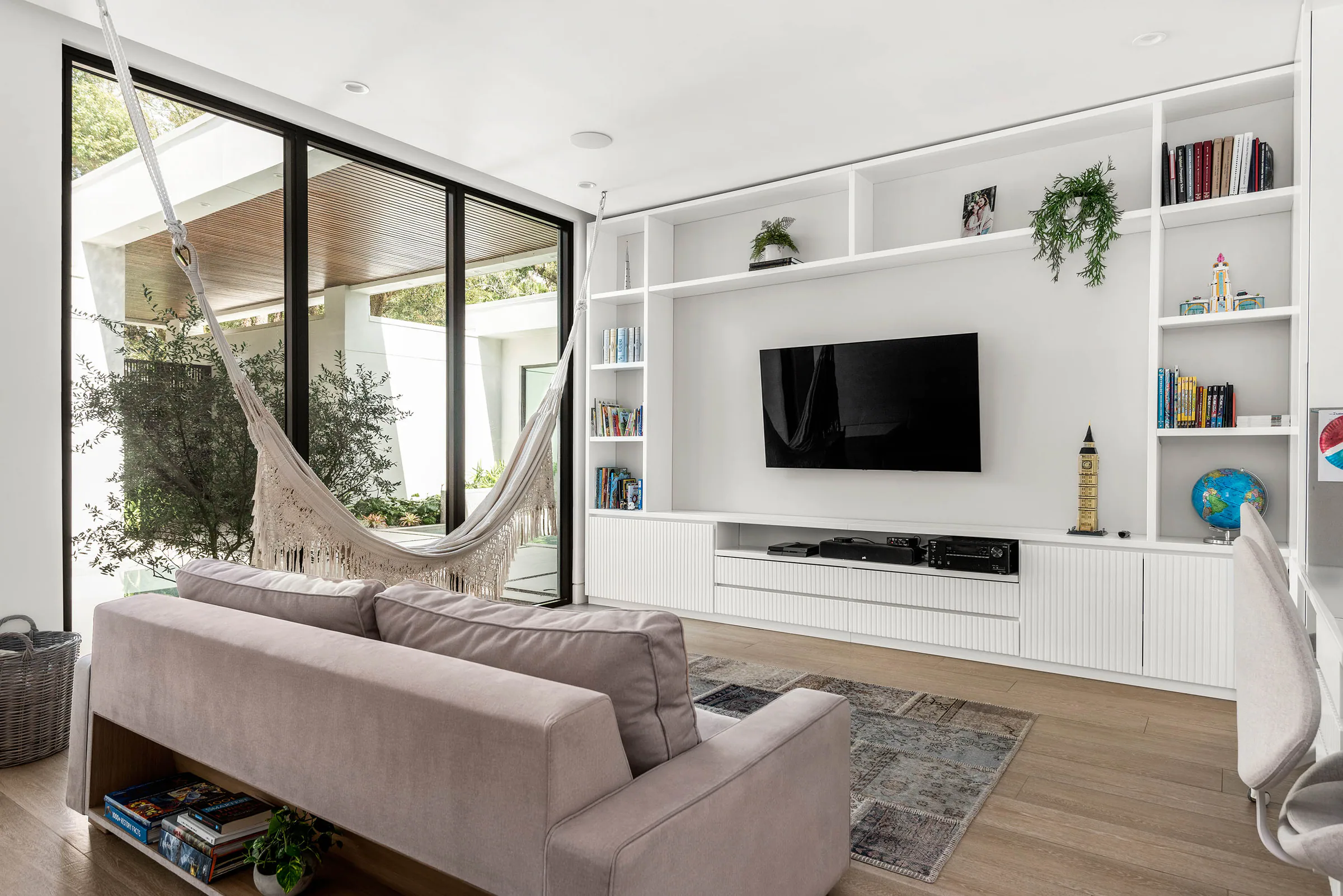 Playroom with pale sectional seating and built-in media wall. Spring, a custom home by Rare Builders in Orlando.