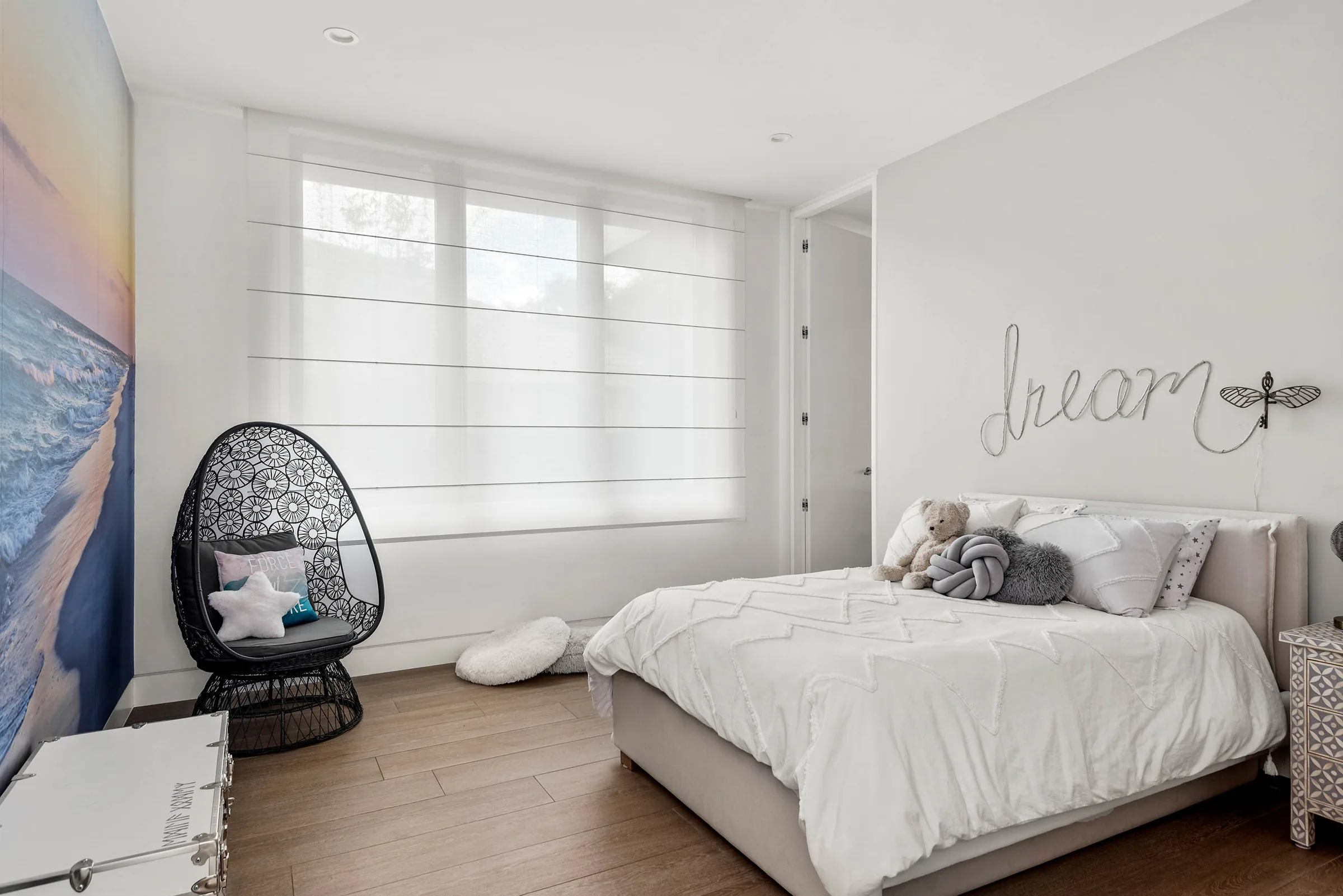 Bedroom with pale bedding and windows on two sides.