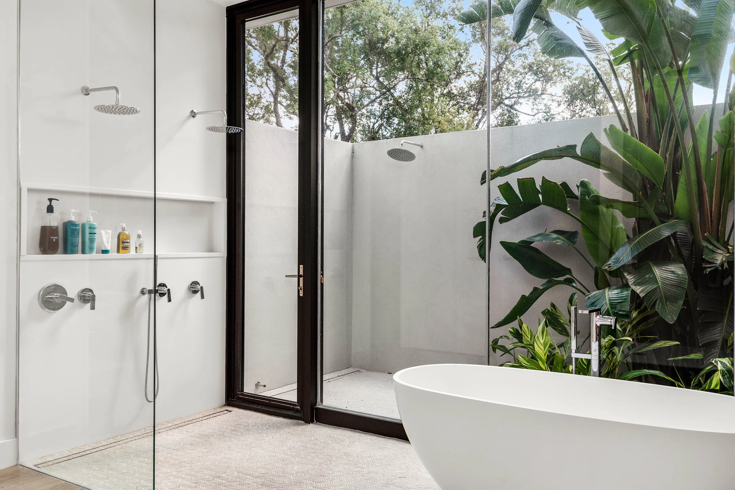 Glass shower opening to a planted private courtyard. Spring, a custom home by Rare Builders in Orlando.
