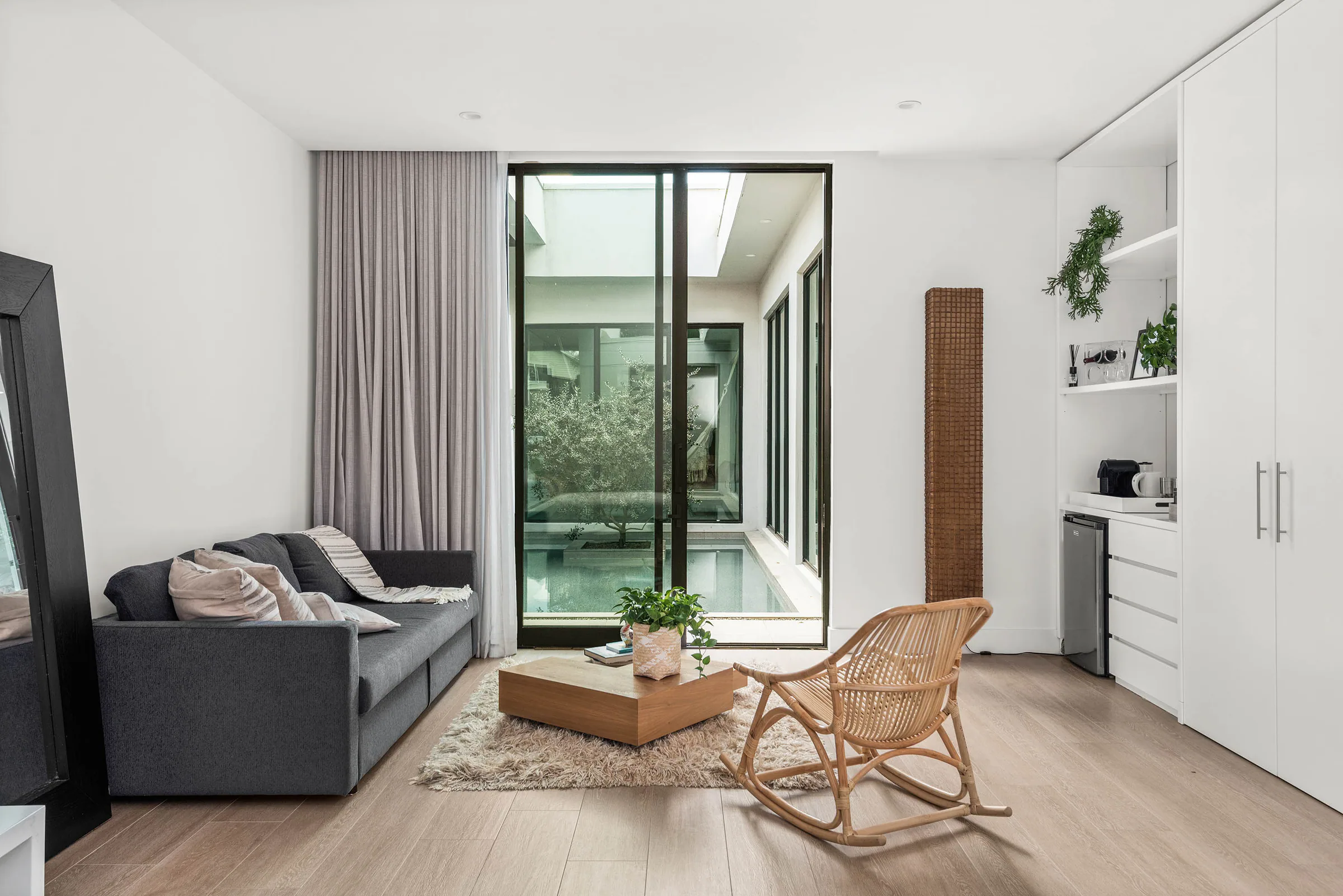 Loft sitting room with a sofa, rocking chair, kitchenette and courtyard view.
