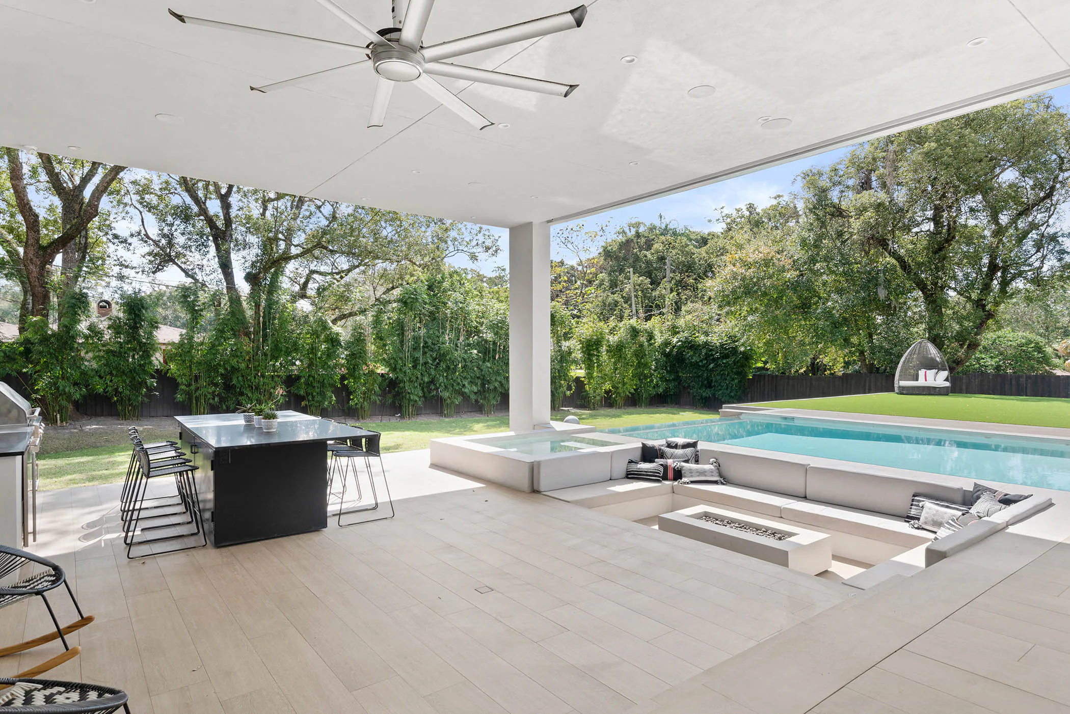 Covered outdoor dining area with wood table and ceiling fan.