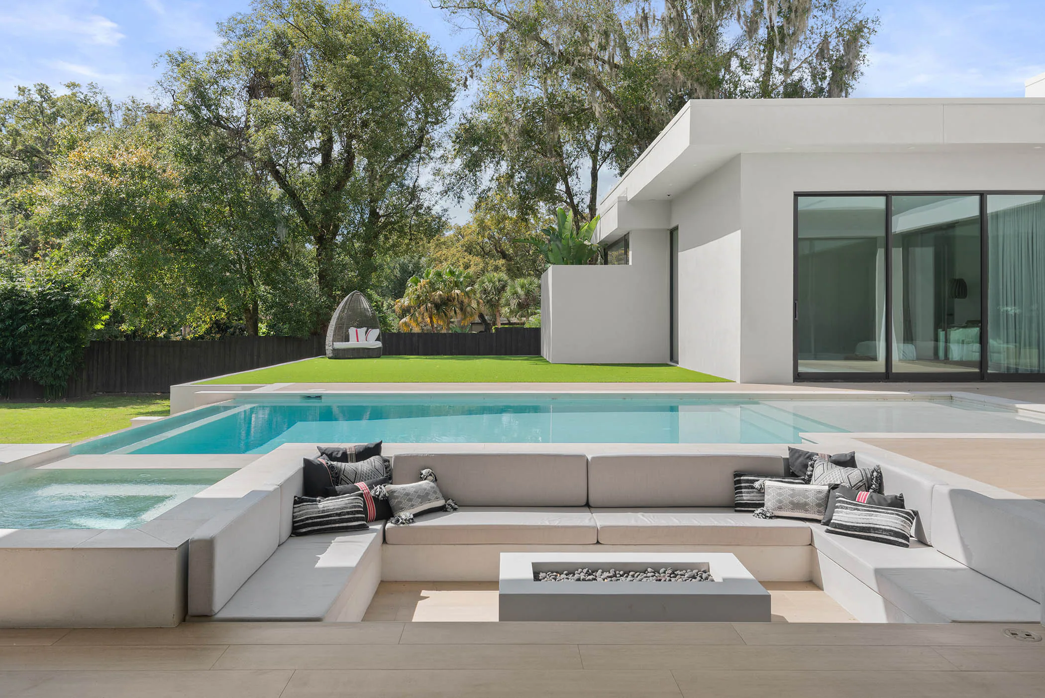 Pool terrace and lawn framed by mature trees. Spring, a custom home by Rare Builders in Orlando.