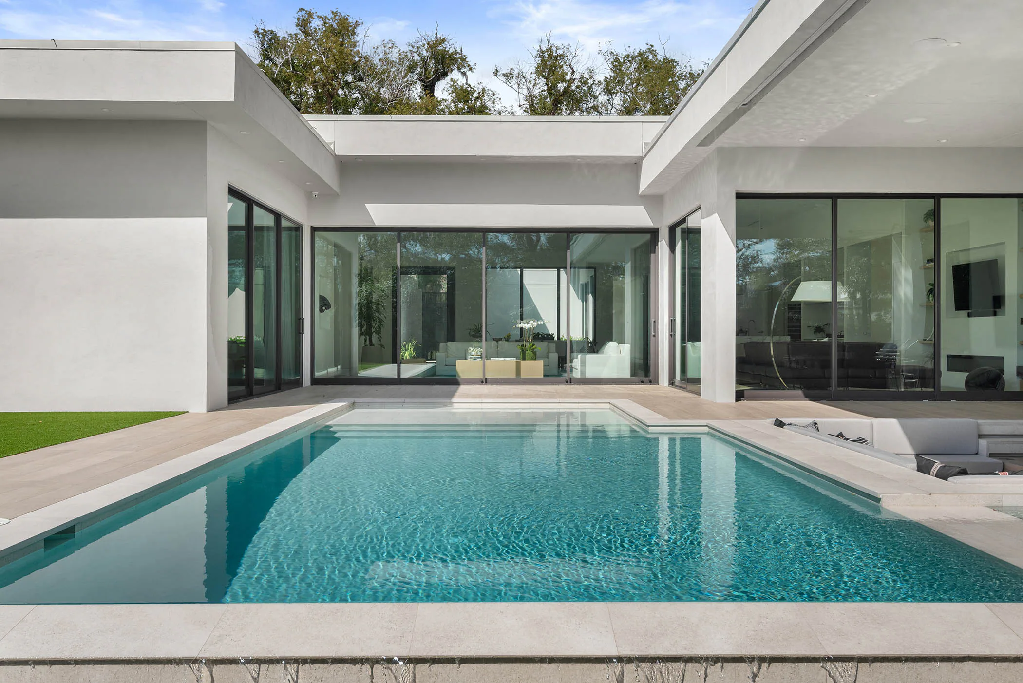 Rectangular pool framed by white walls and dark glazing.