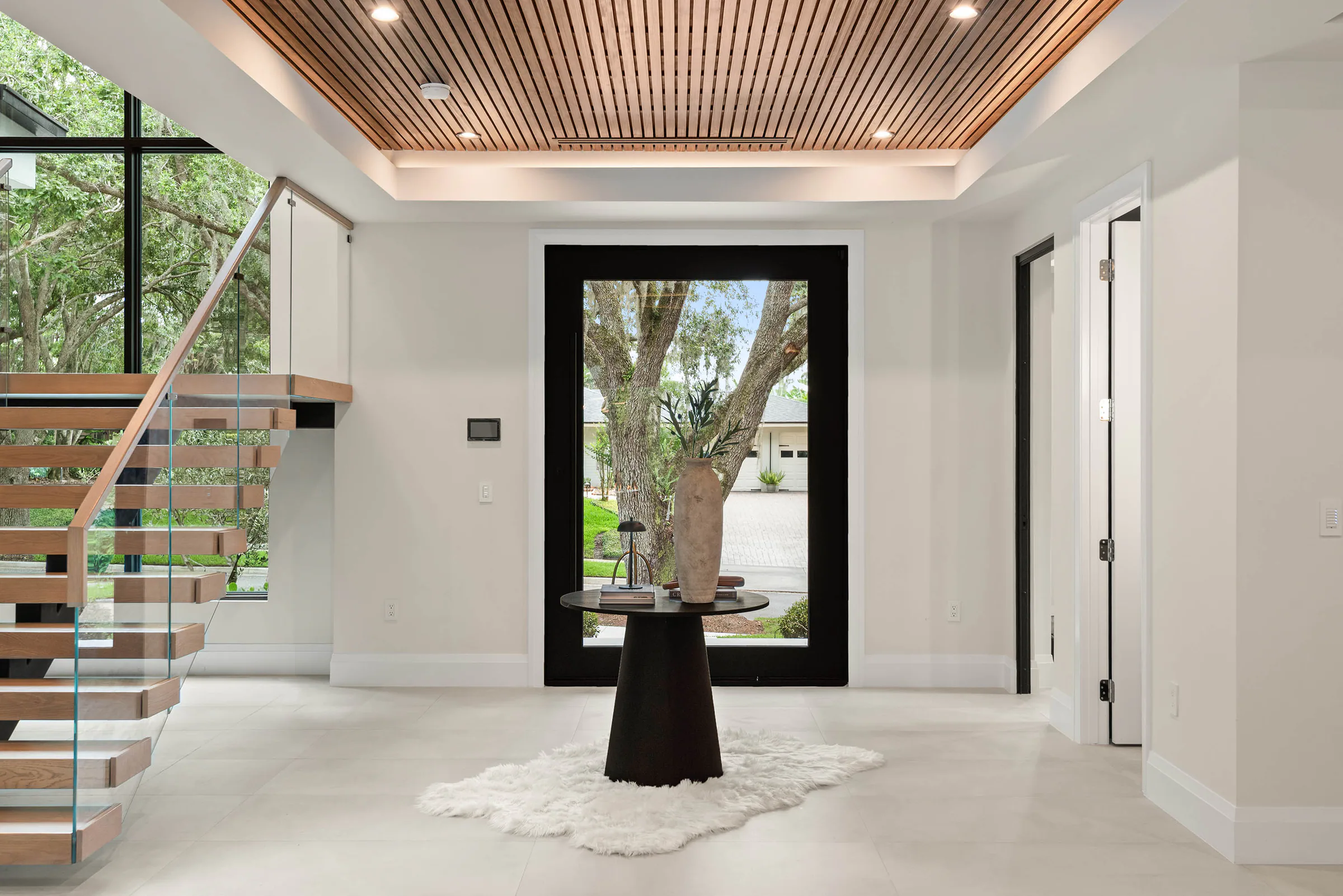 Bright entry hall with floating stair and dark-framed garden doors.
