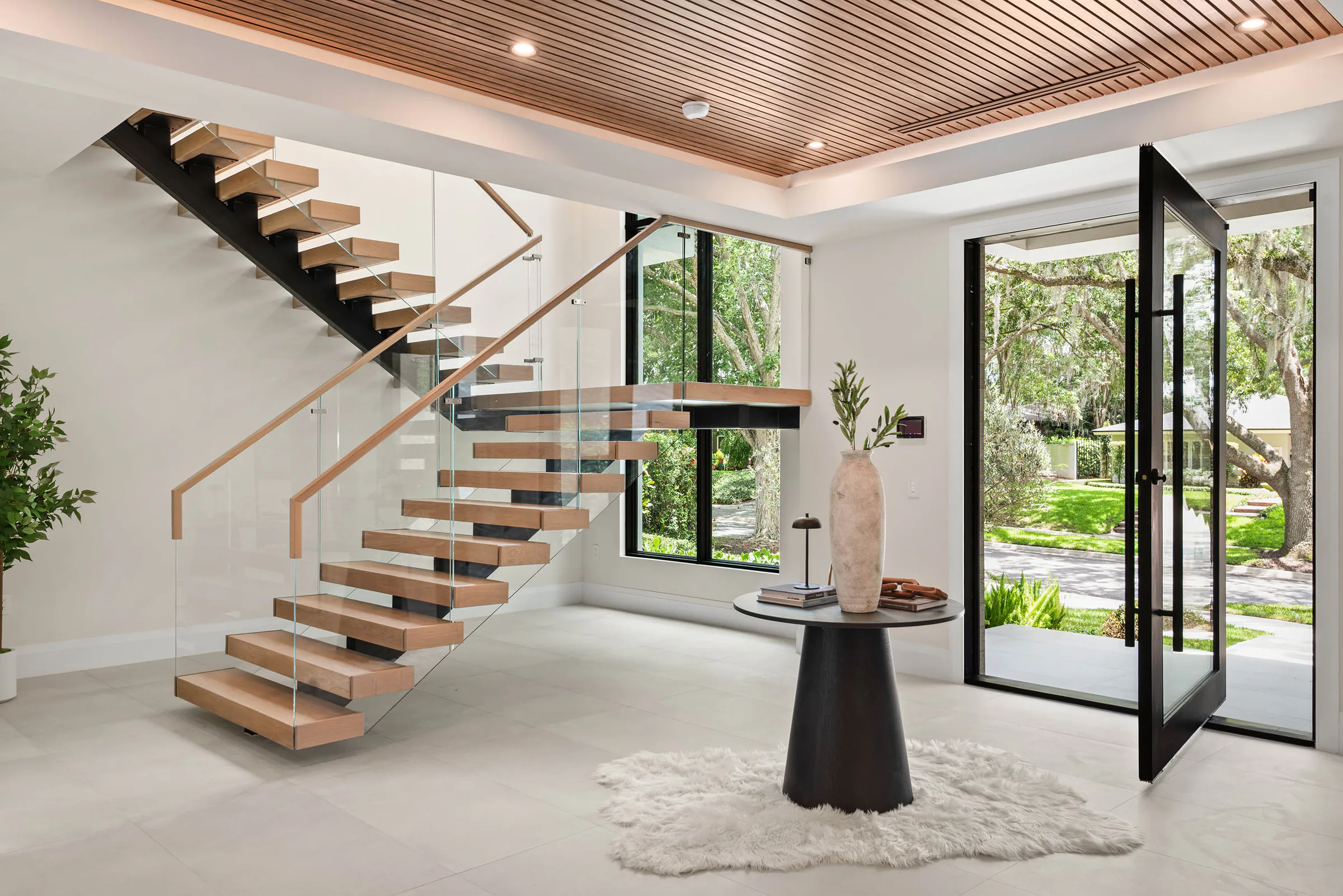 Floating wood staircase beneath a perforated wood ceiling.