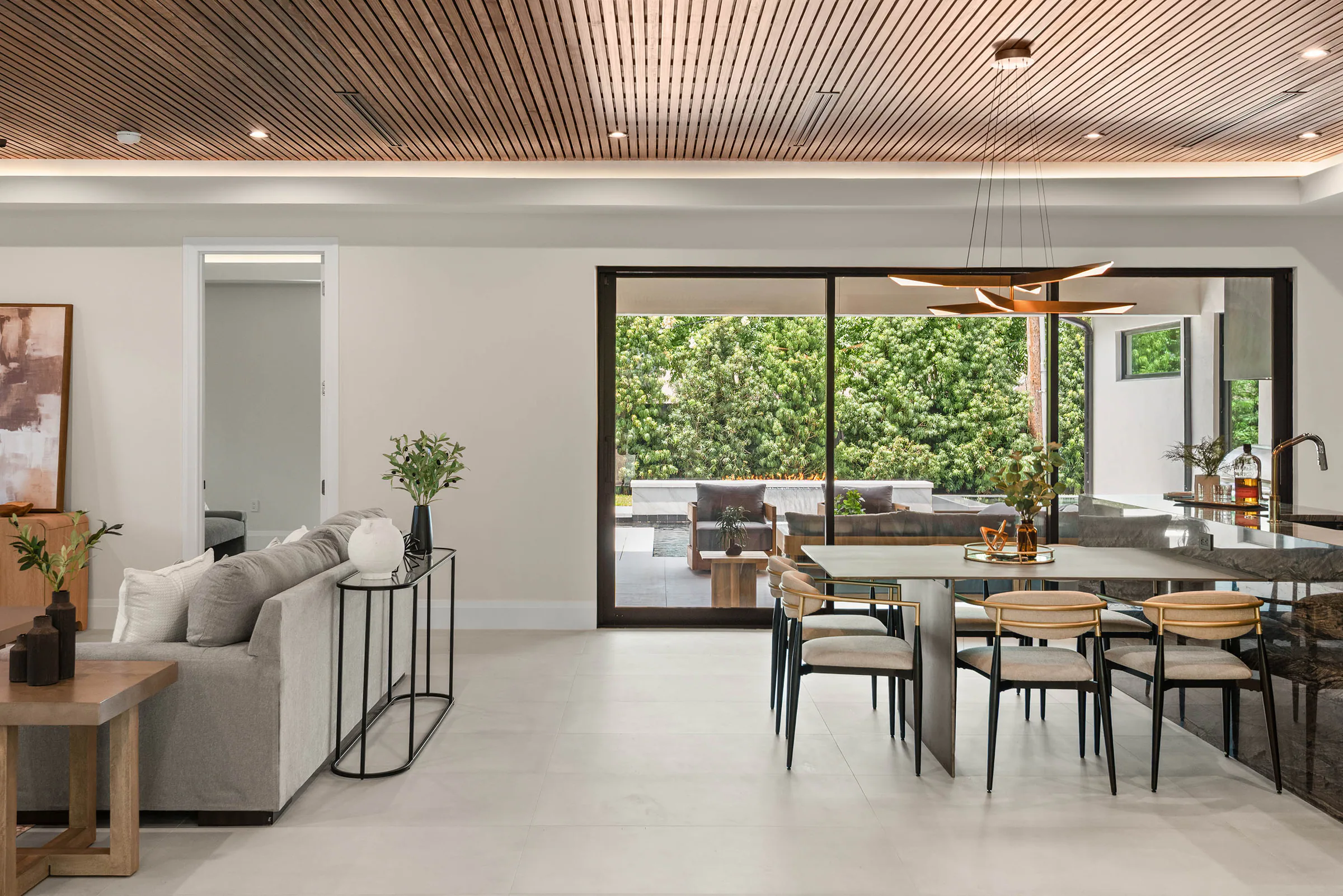 Open dining area beneath a perforated wood ceiling facing the garden.