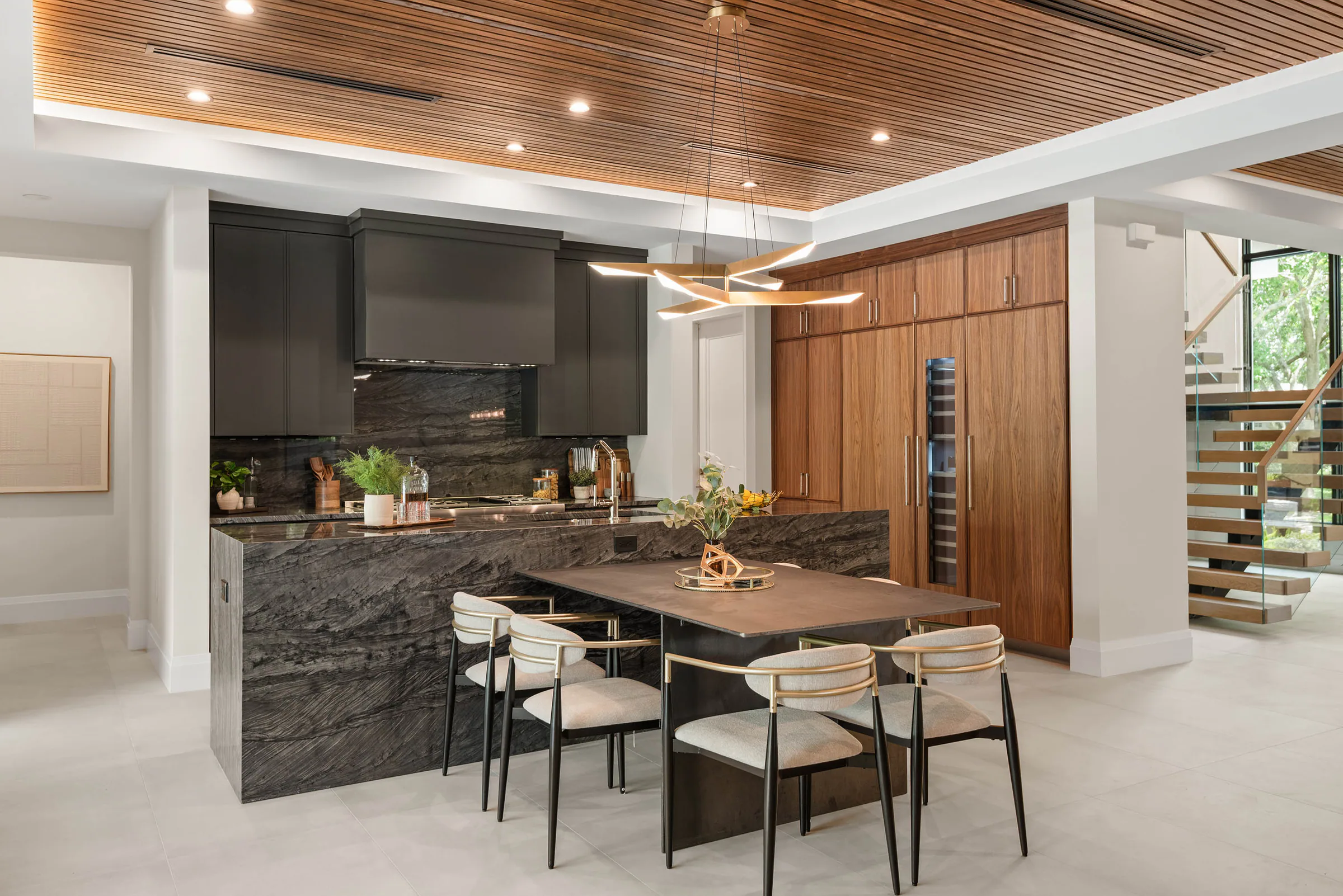 Dark marble kitchen island with wood cabinetry and black hood. Munster, a custom home by Rare Builders in Orlando.