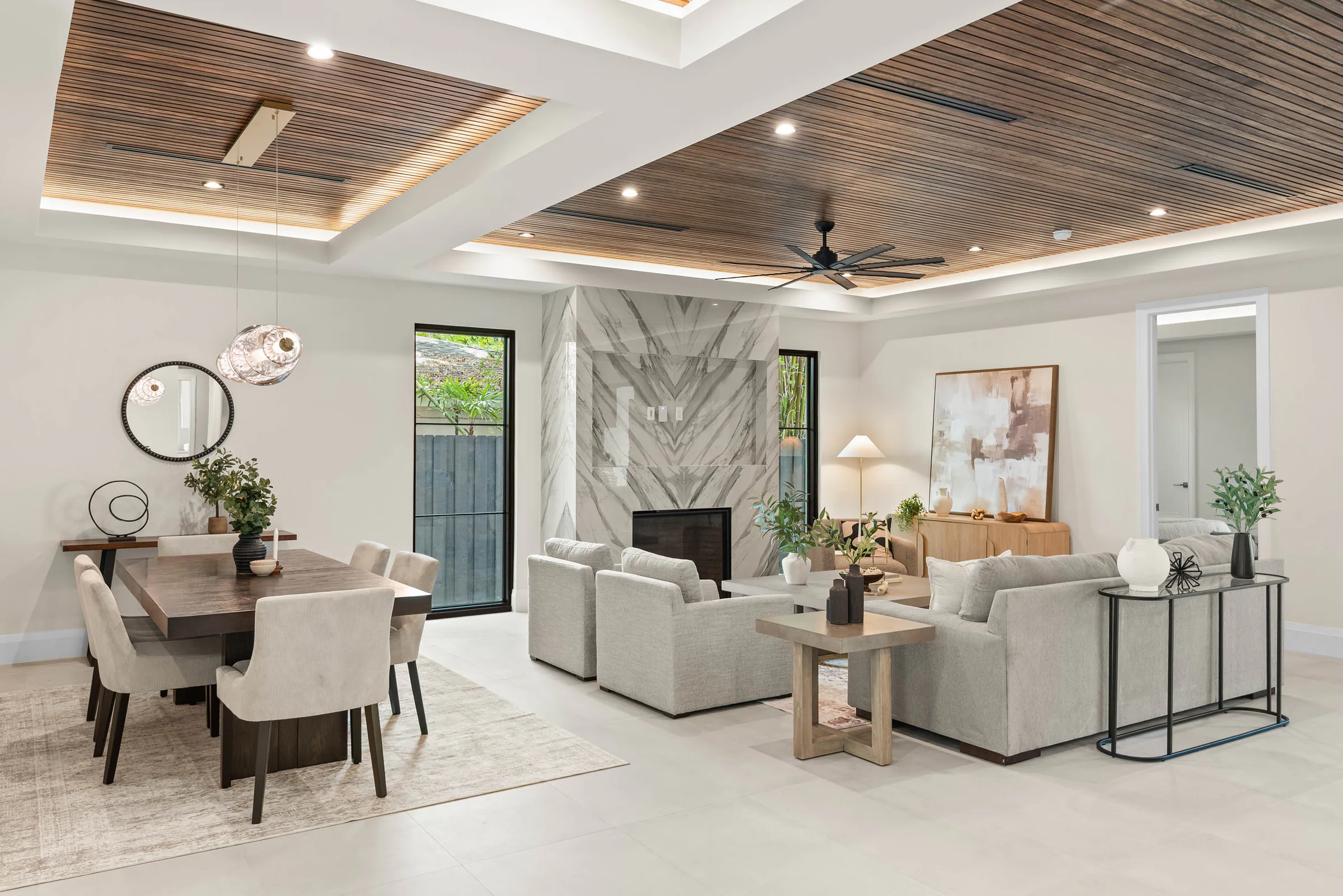 Living room with pale seating and a veined stone fireplace. Munster, a custom home by Rare Builders in Orlando.