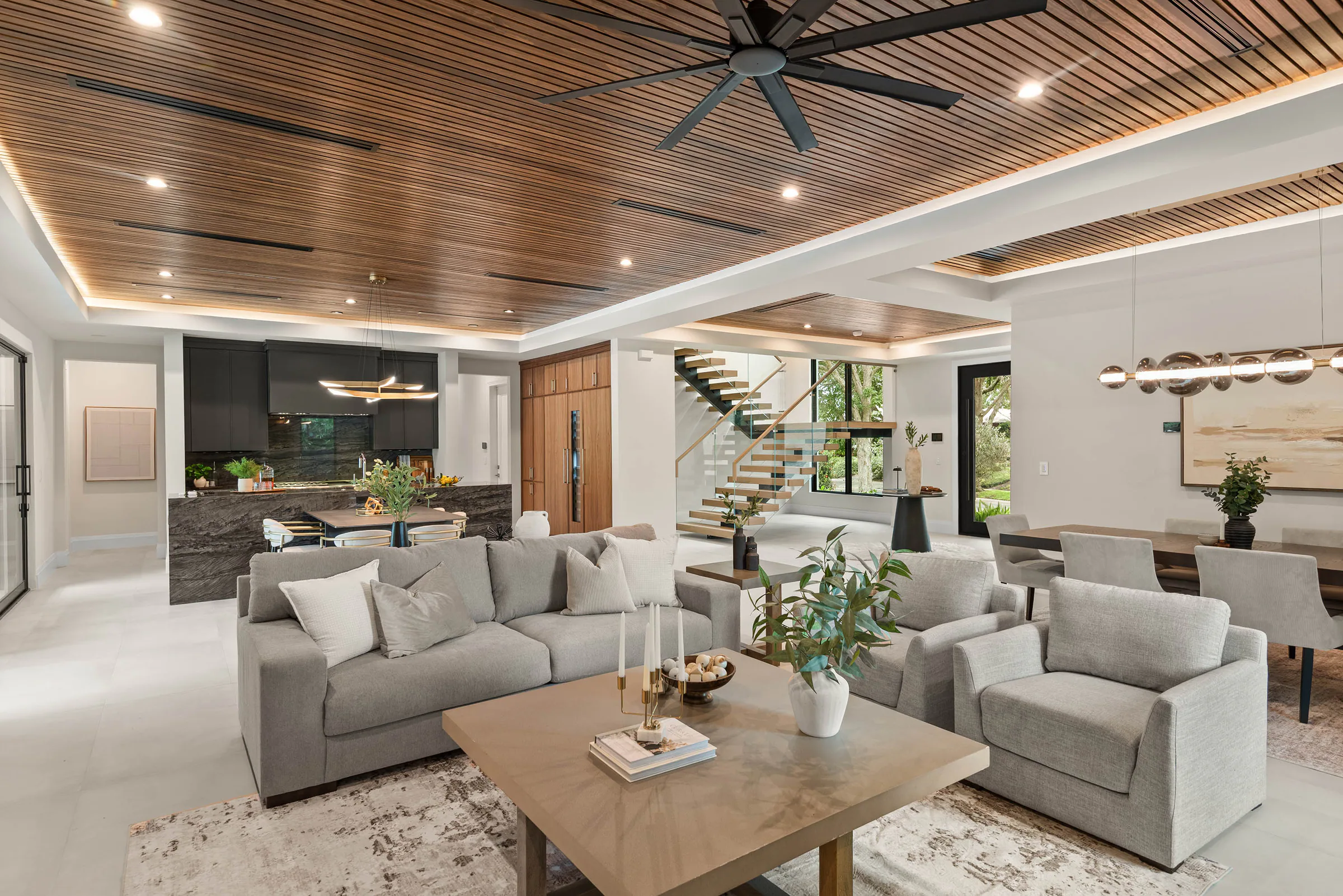 Living room beneath a perforated wood ceiling beside the kitchen. Munster, a custom home by Rare Builders in Orlando.