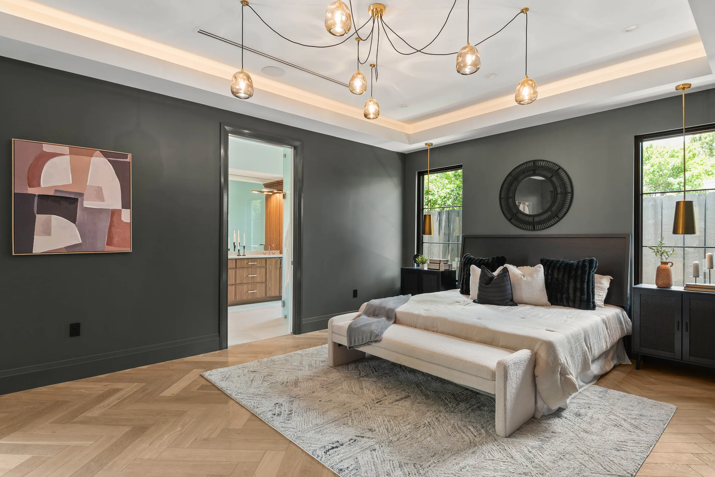 Bedroom with deep green walls, upholstered bed and brass pendants. Munster, a custom home by Rare Builders in Orlando.