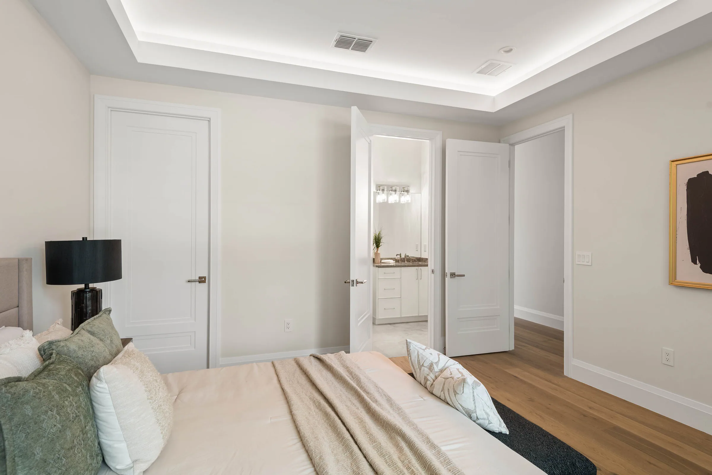 Bedroom with pale bedding and a large black-framed window. Munster, a custom home by Rare Builders in Orlando.