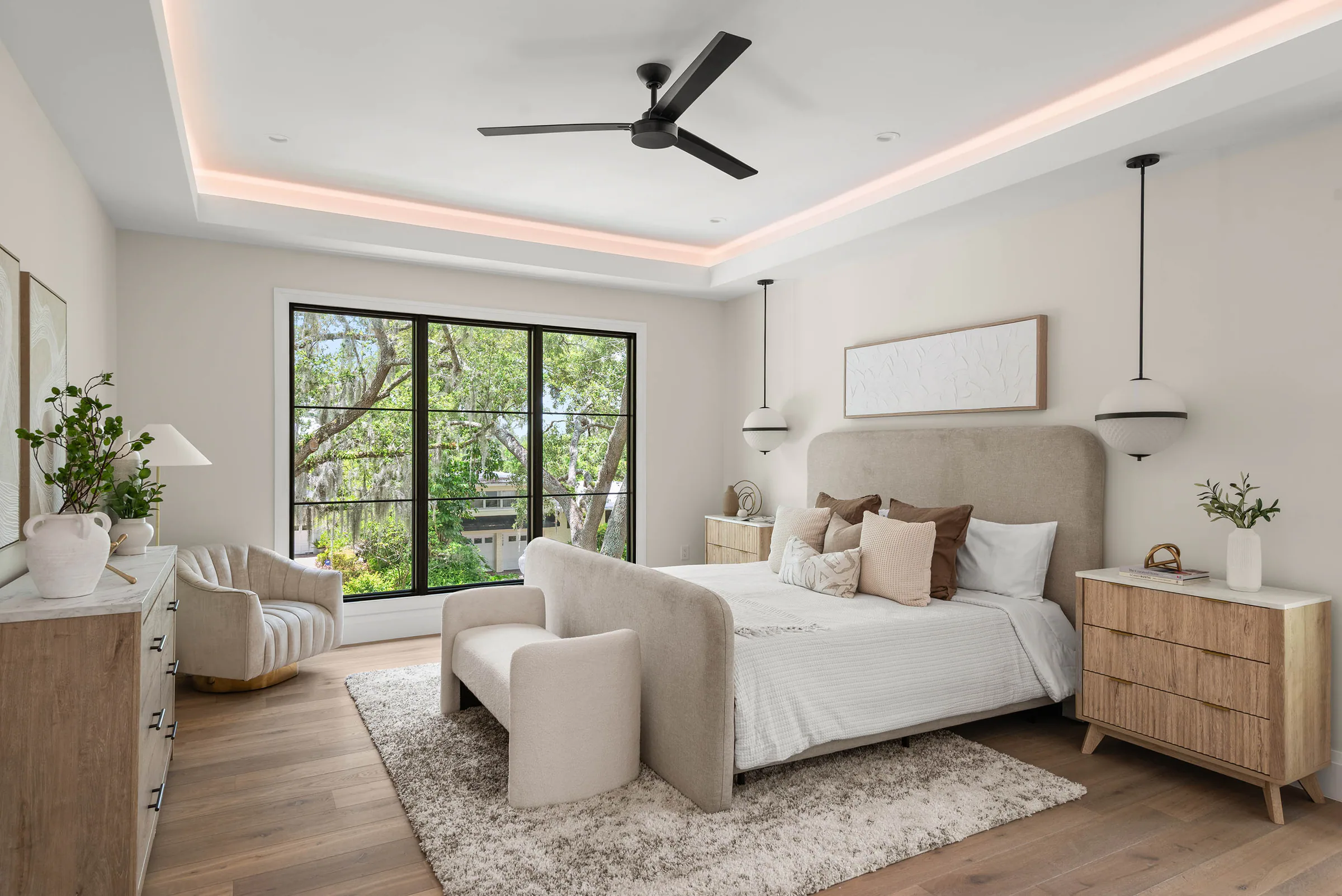 Bedroom with pale seating and dark-framed garden doors. Munster, a custom home by Rare Builders in Orlando.