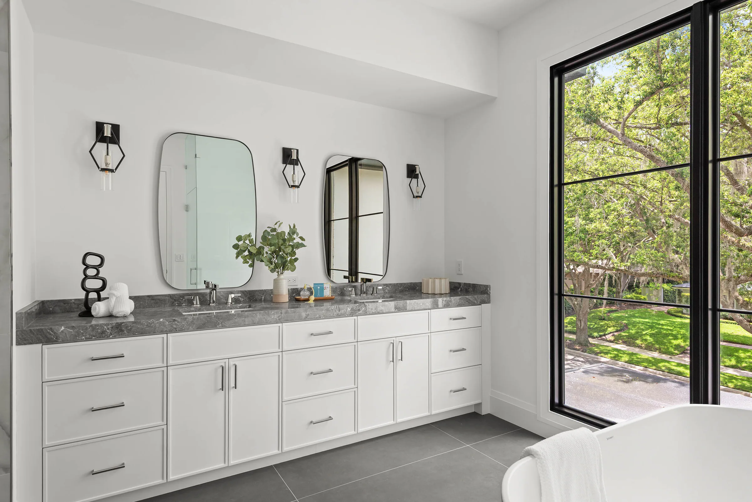 Long white vanity with twin mirrors and black fixtures.