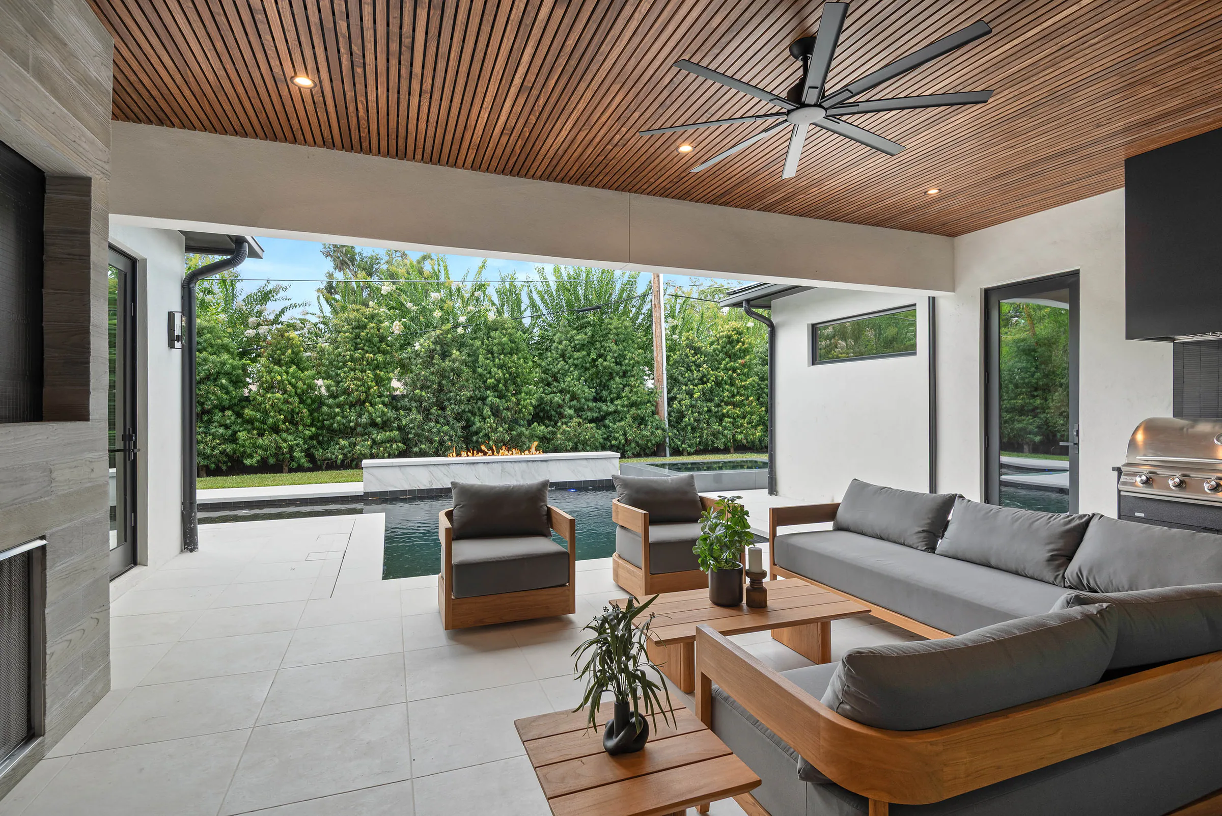 Covered outdoor lounge beneath a perforated wood ceiling. Munster, a custom home by Rare Builders in Orlando.