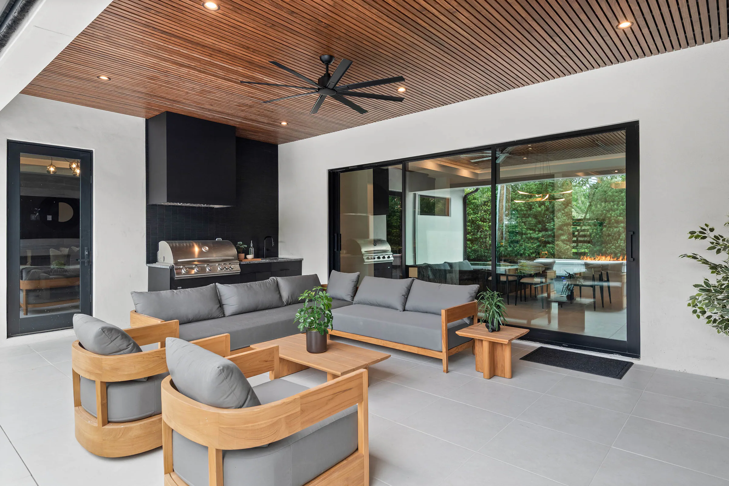Outdoor kitchen and dining area opening to the pool. Munster, a custom home by Rare Builders in Orlando.