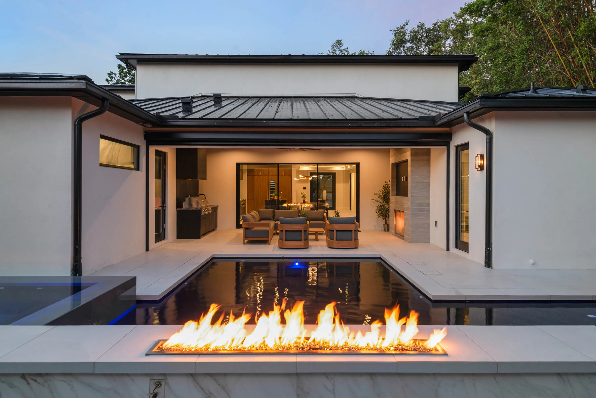 Rear pavilion and fire feature glowing at dusk.