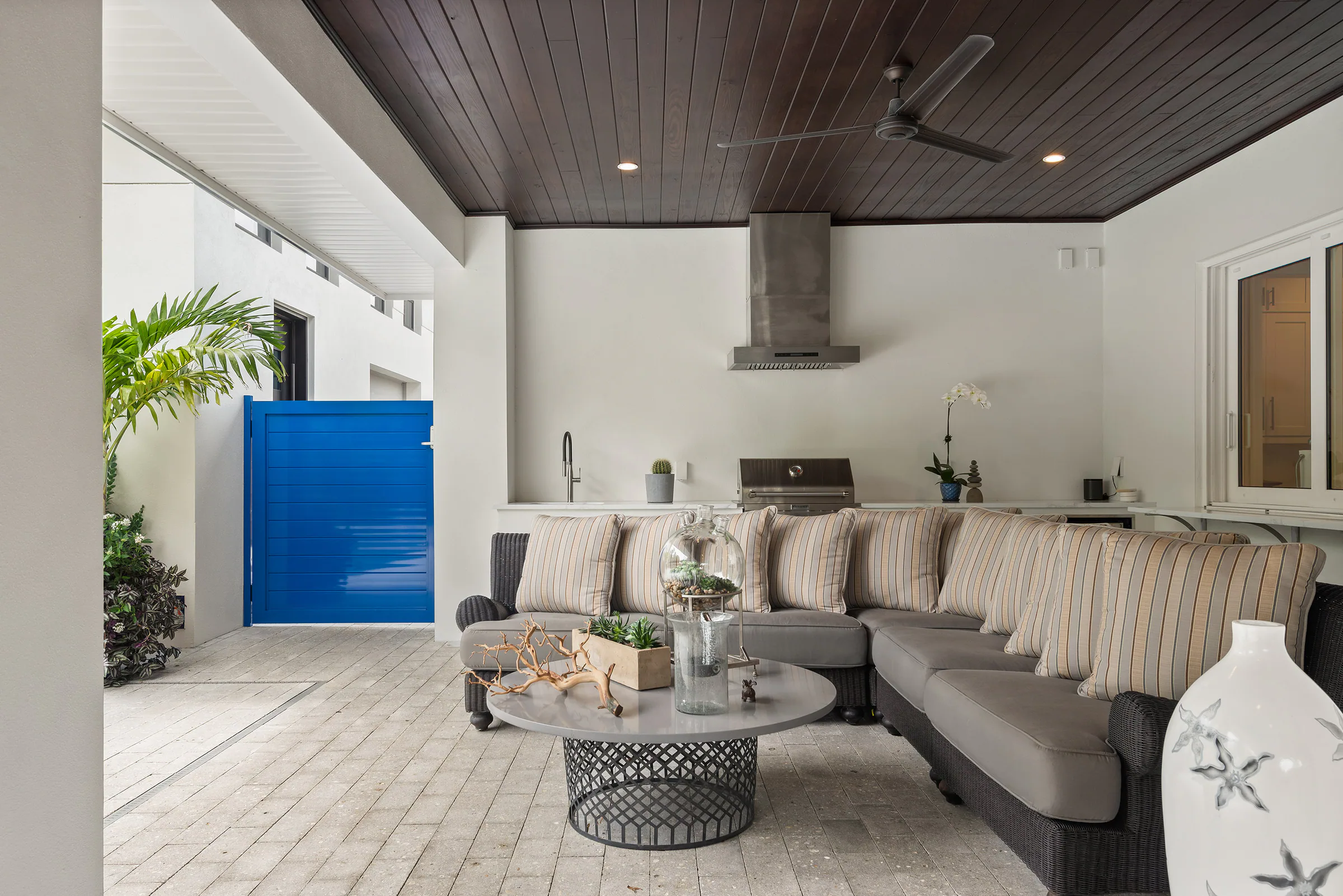 Covered rear lounge with wood ceiling and pale seating. Nottingham, a custom home by Rare Builders in Orlando.