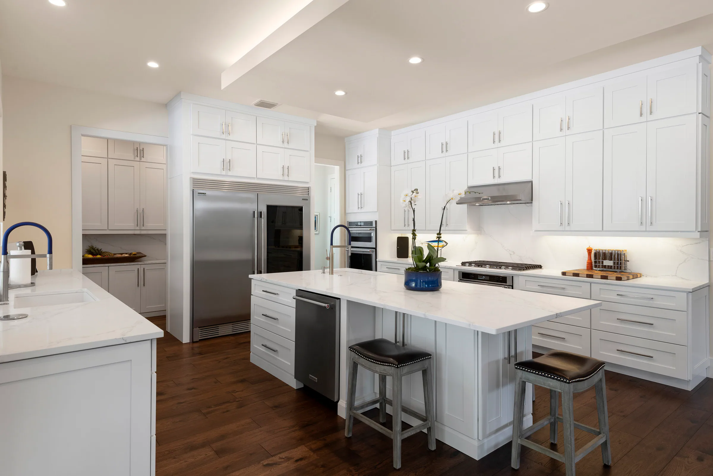 White kitchen island beneath pendant lights. Nottingham, a custom home by Rare Builders in Orlando.