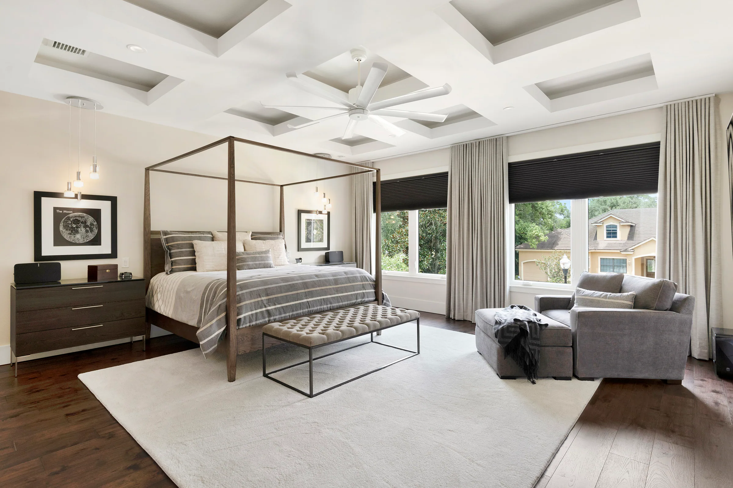 Bedroom with a coffered ceiling and broad black-framed bed. Nottingham, a custom home by Rare Builders in Orlando.