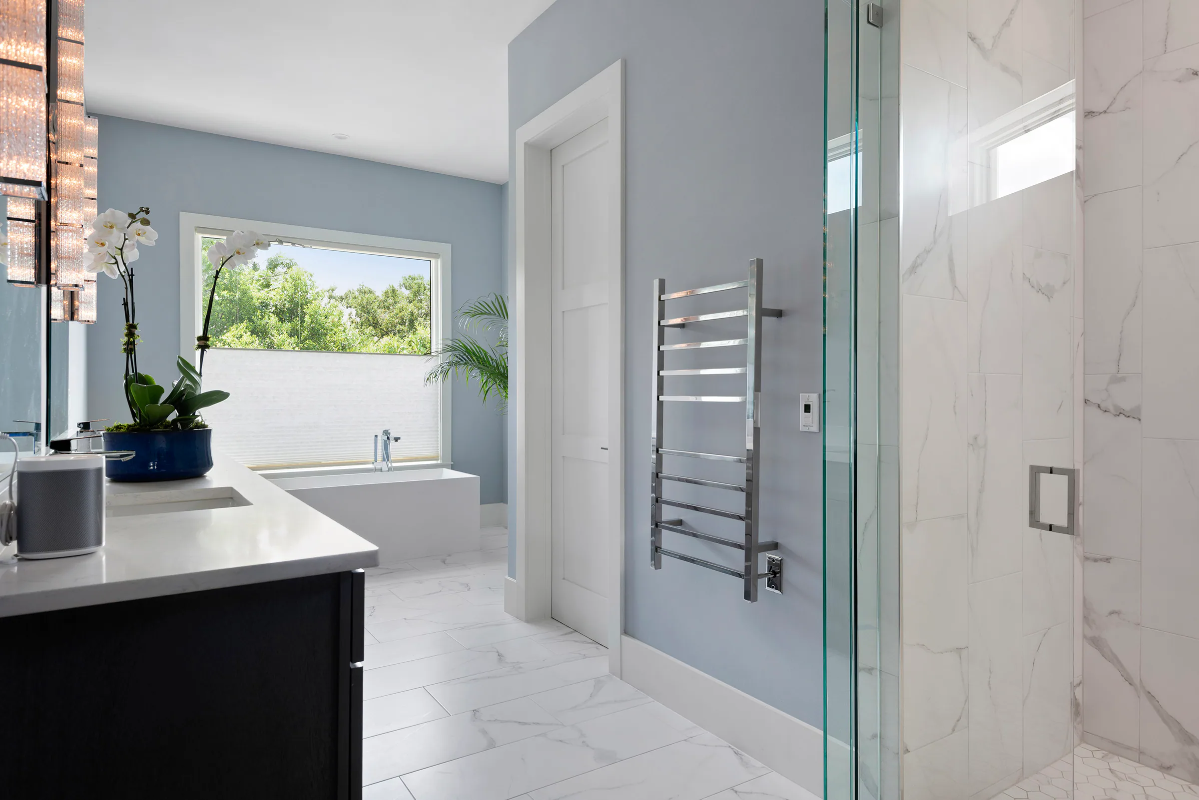 Bathroom with twin vanity, glass shower and pale stone finishes.