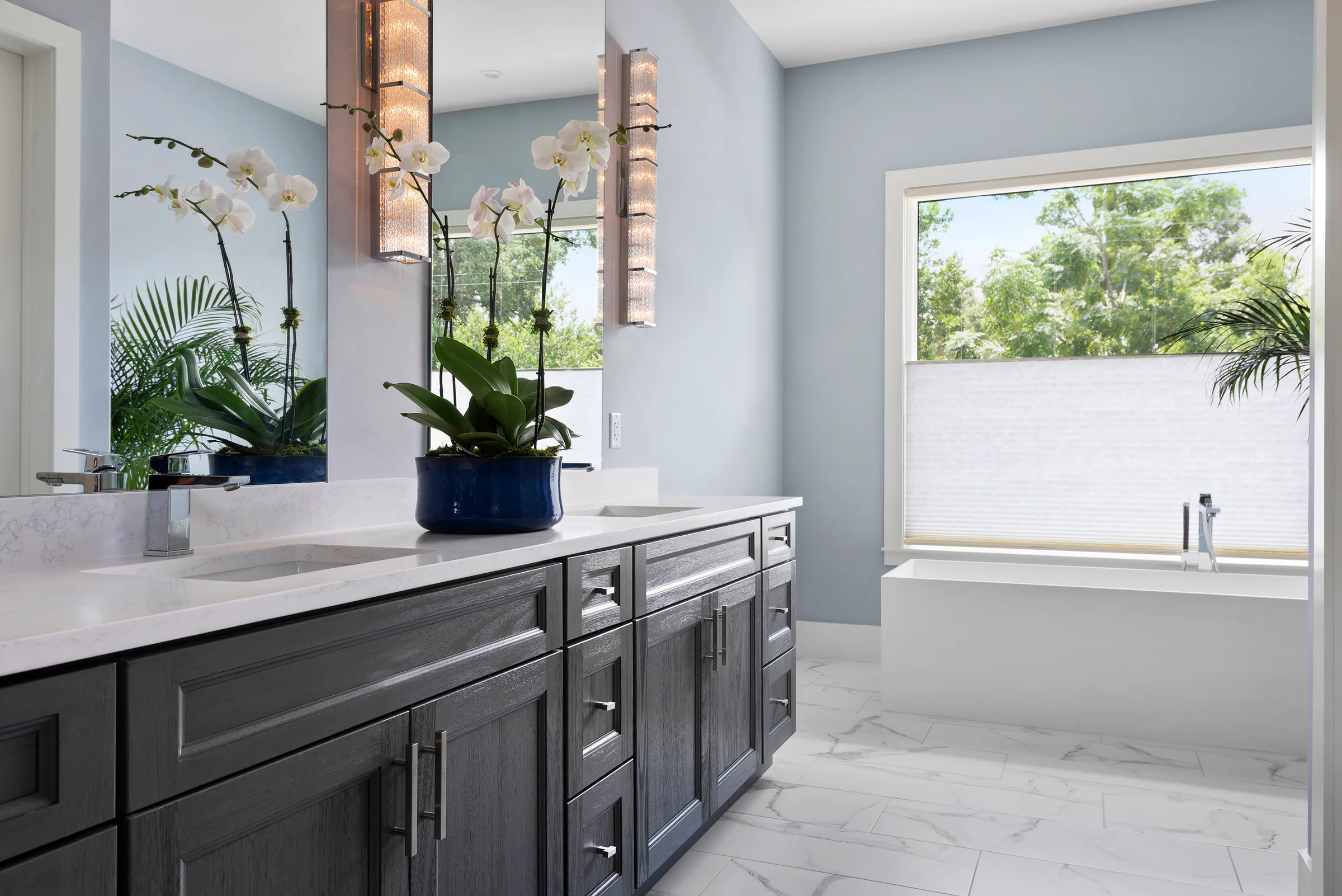 Dark wood vanity and glass shower beneath a broad mirror. Nottingham, a custom home by Rare Builders in Orlando.