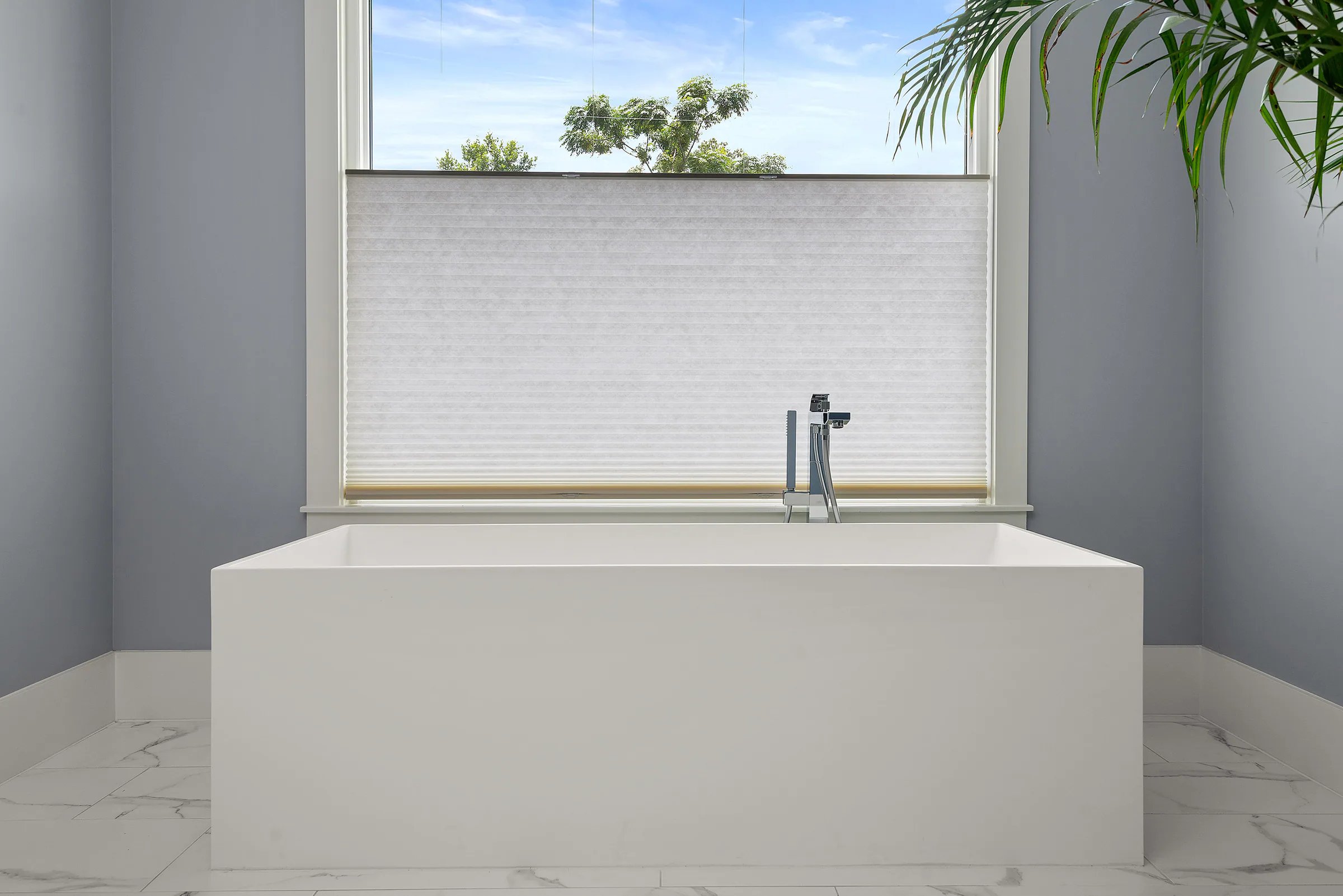 Freestanding tub beneath a high horizontal window. Nottingham, a custom home by Rare Builders in Orlando.