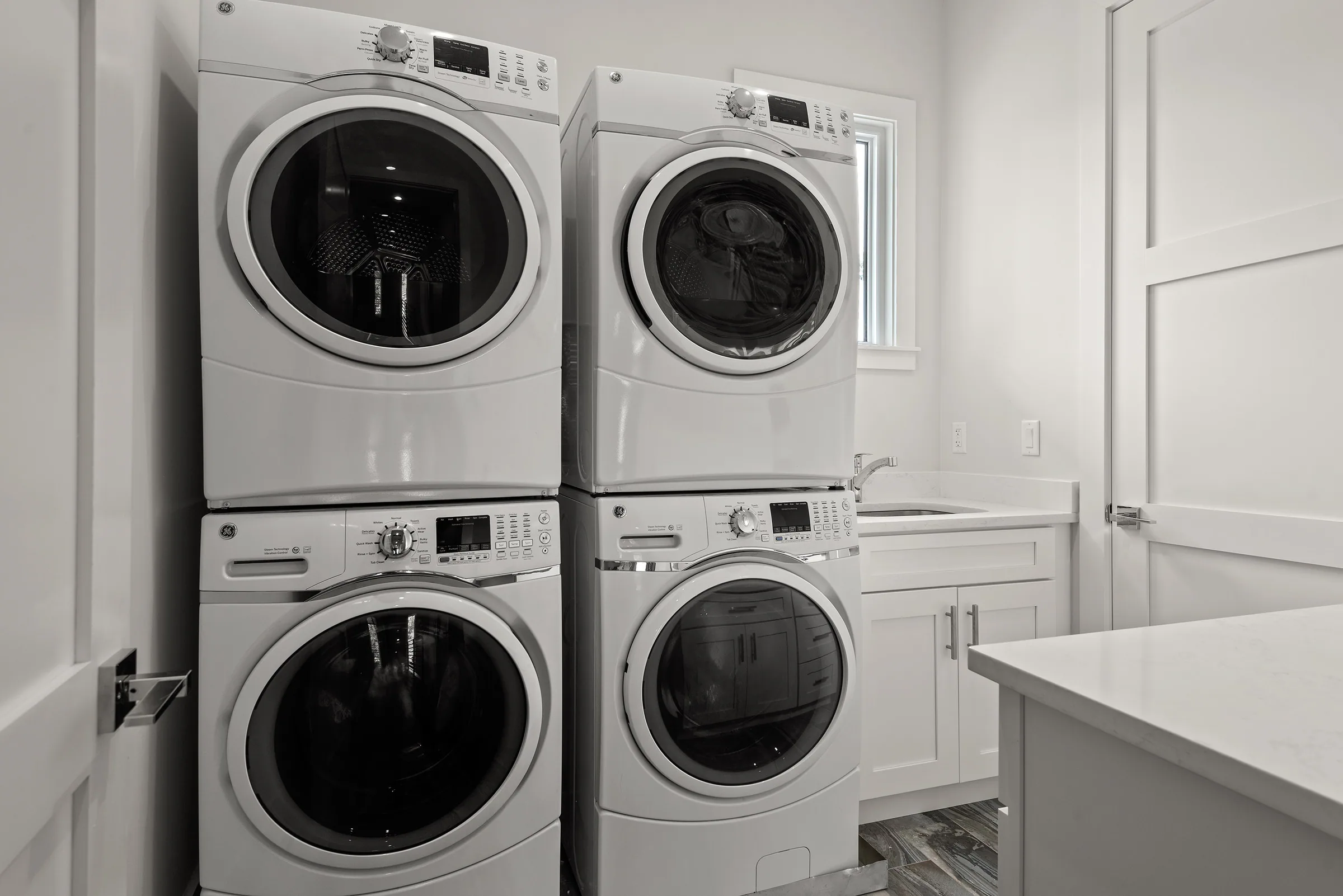 Stacked laundry machines beneath white cabinetry.