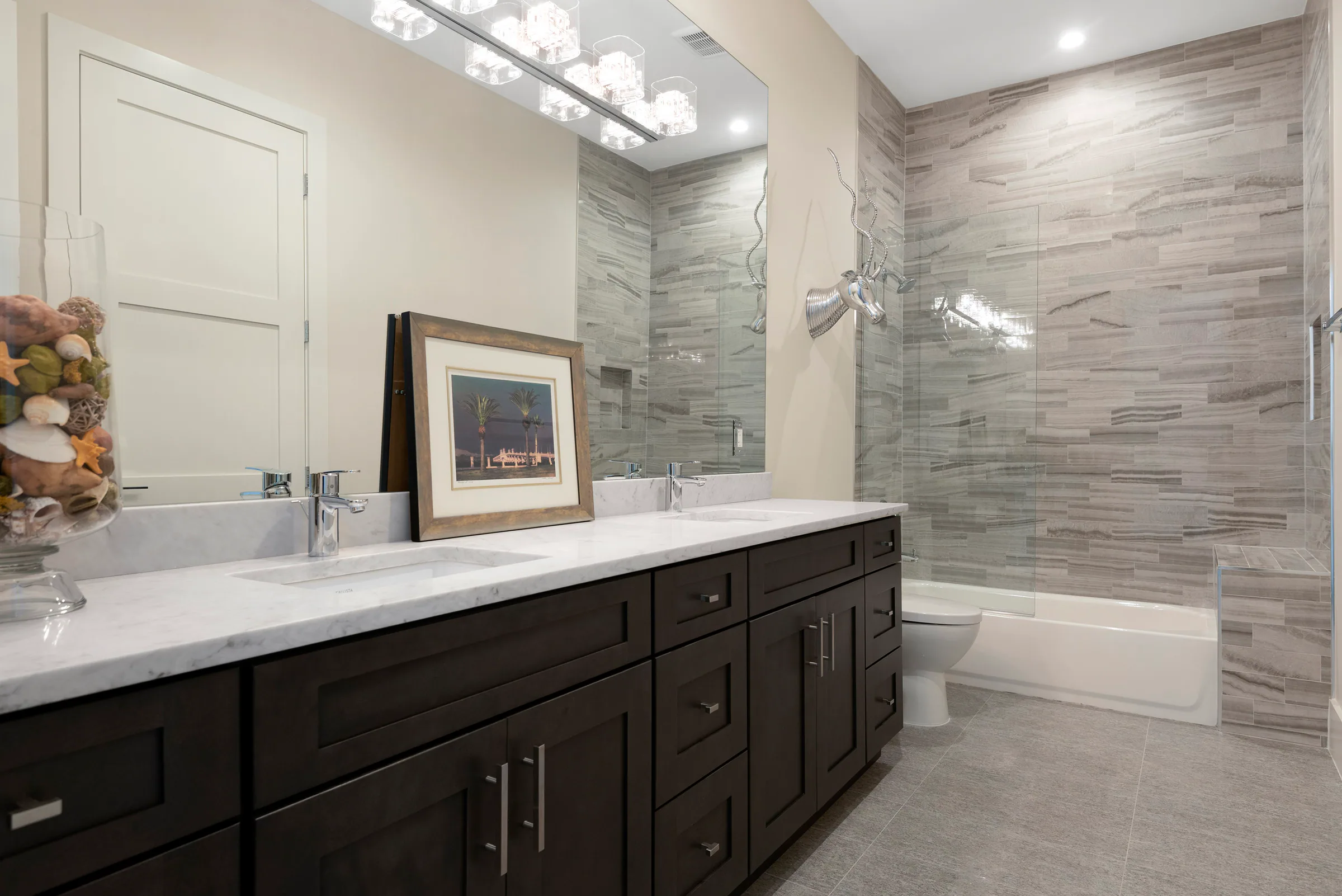 Long dark vanity and glass shower in a bright bathroom.