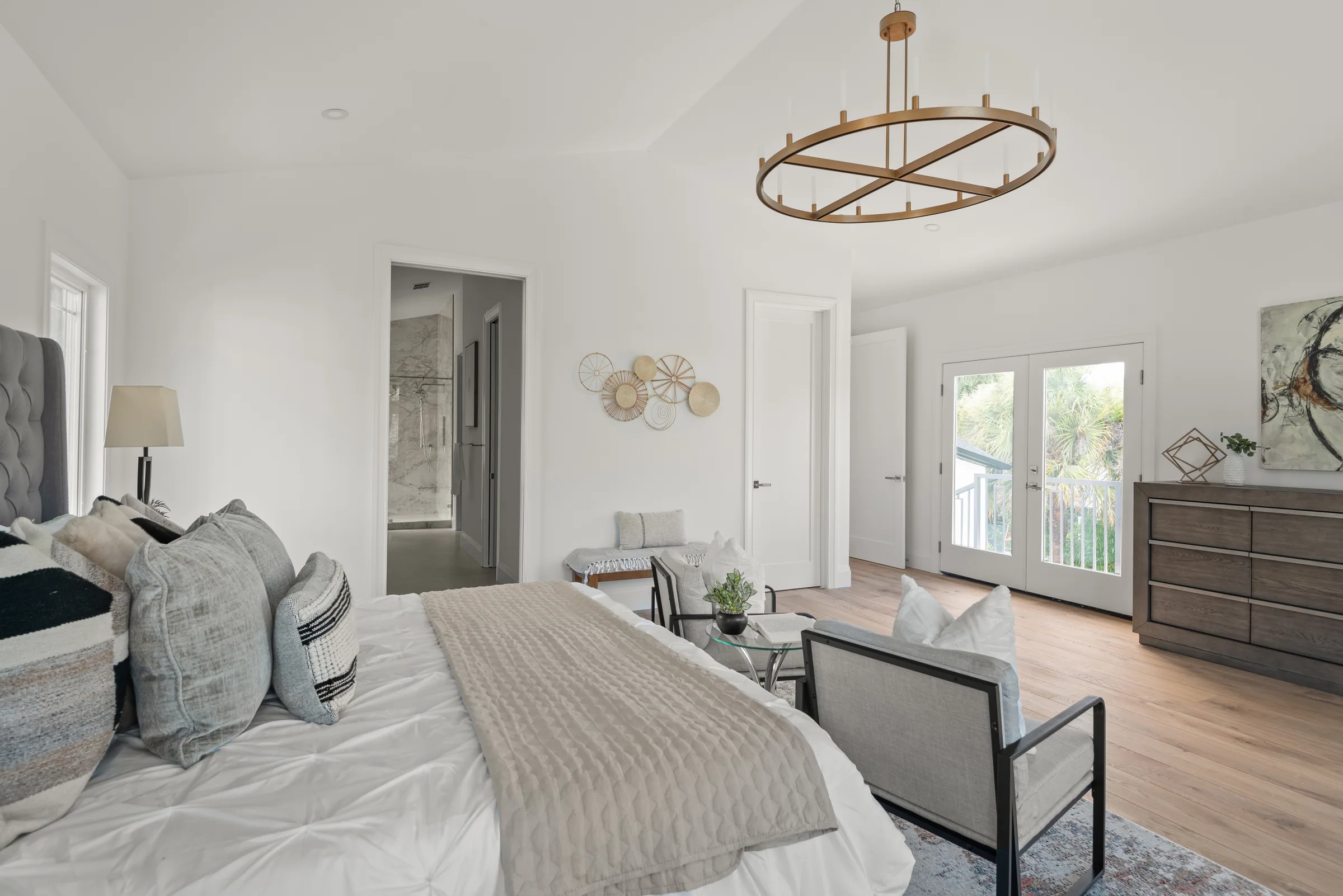 Bedroom with a ring chandelier, wood-toned floor and glazed doors opening toward the upper balcony.