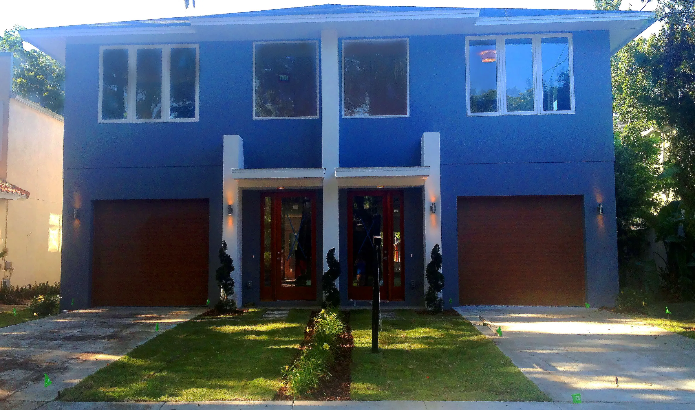 West Harvard’s blue two-story facade with paired central entry doors, separate garages and white window trim.