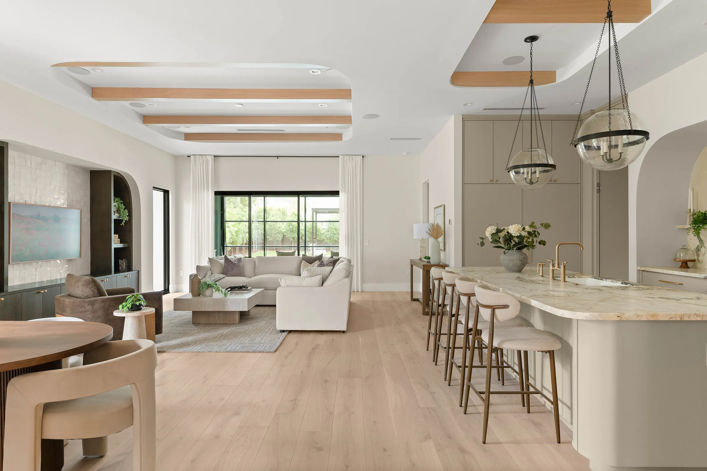 Open living, dining and kitchen volume beneath wood-trimmed ceiling beams. Dana, a custom home by Rare Builders in Orlando.