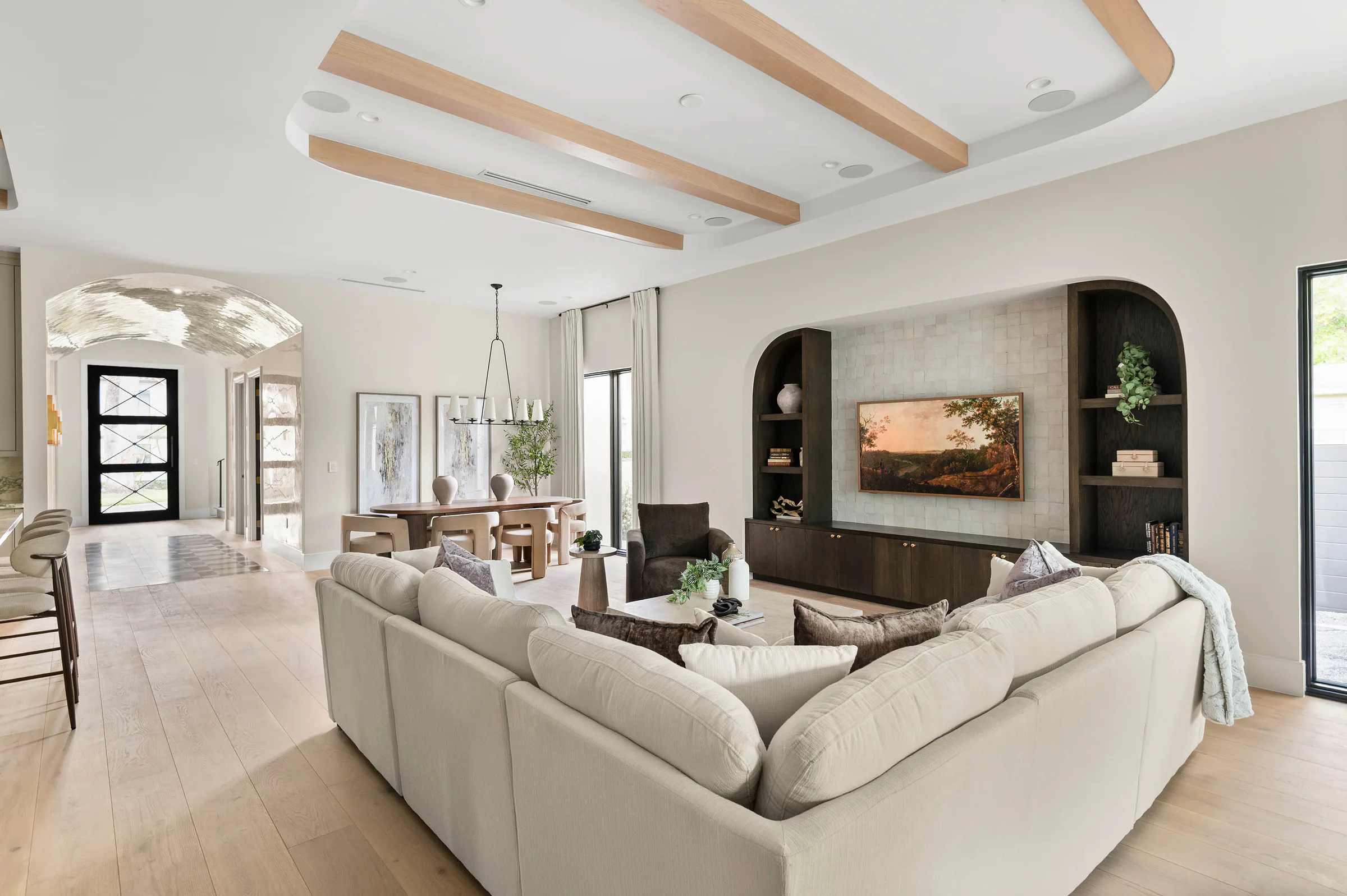 Living room with pale seating and dark arched built-ins.