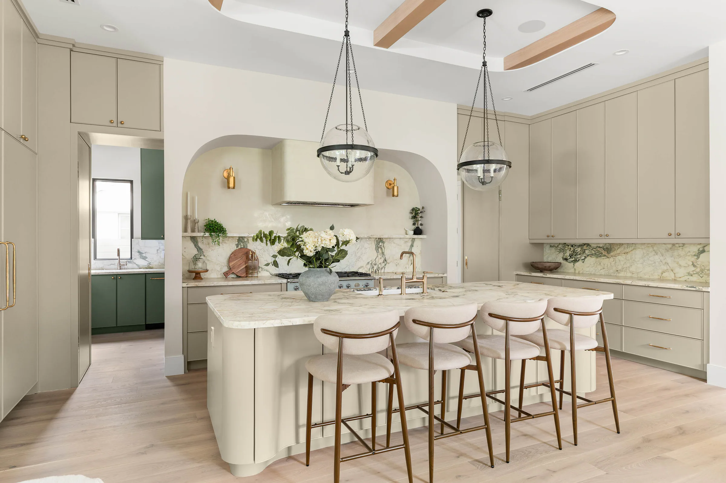 Marble-topped island with upholstered stools and pale cabinetry.
