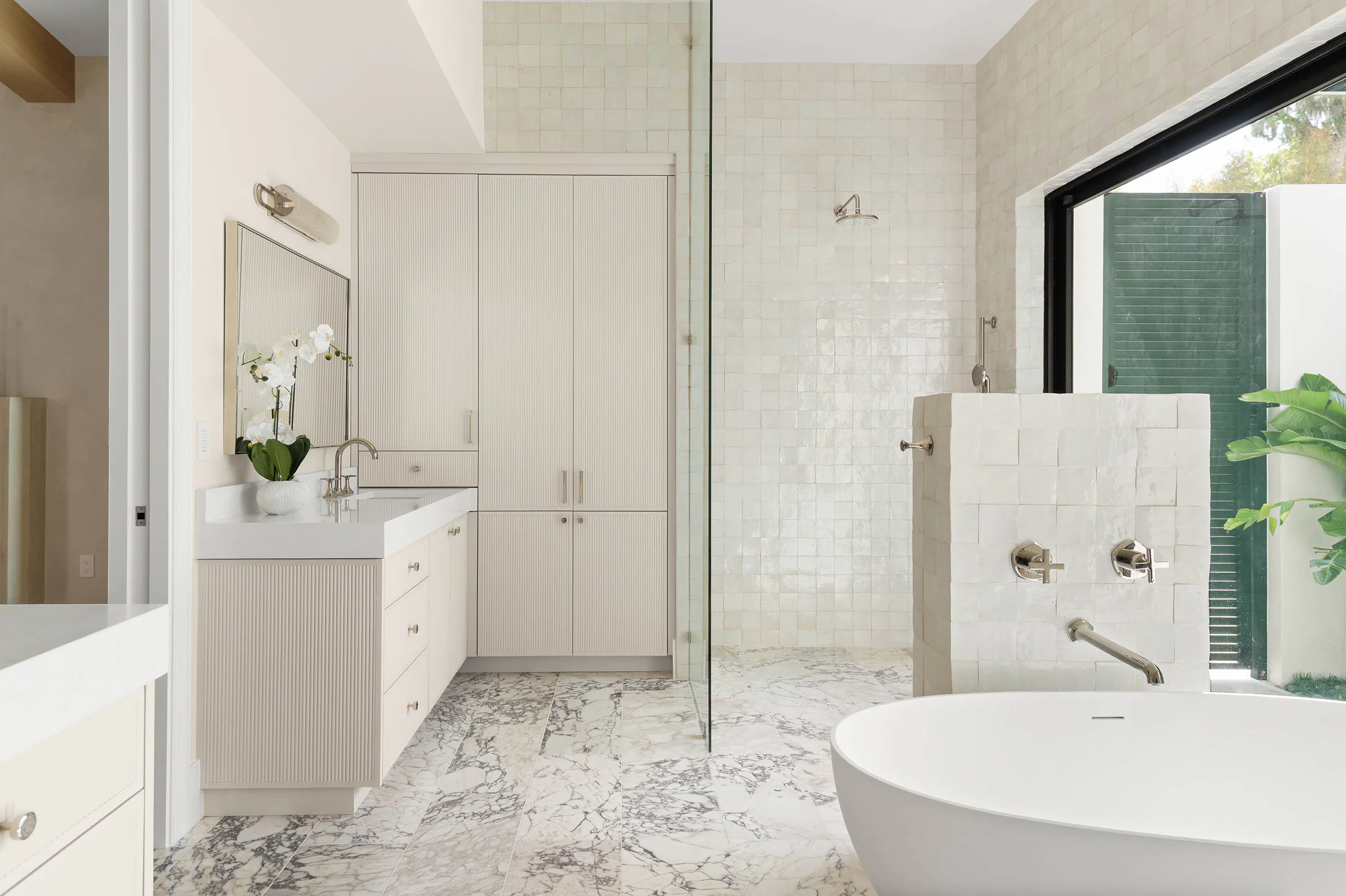 Freestanding tub beside a black-framed garden window.