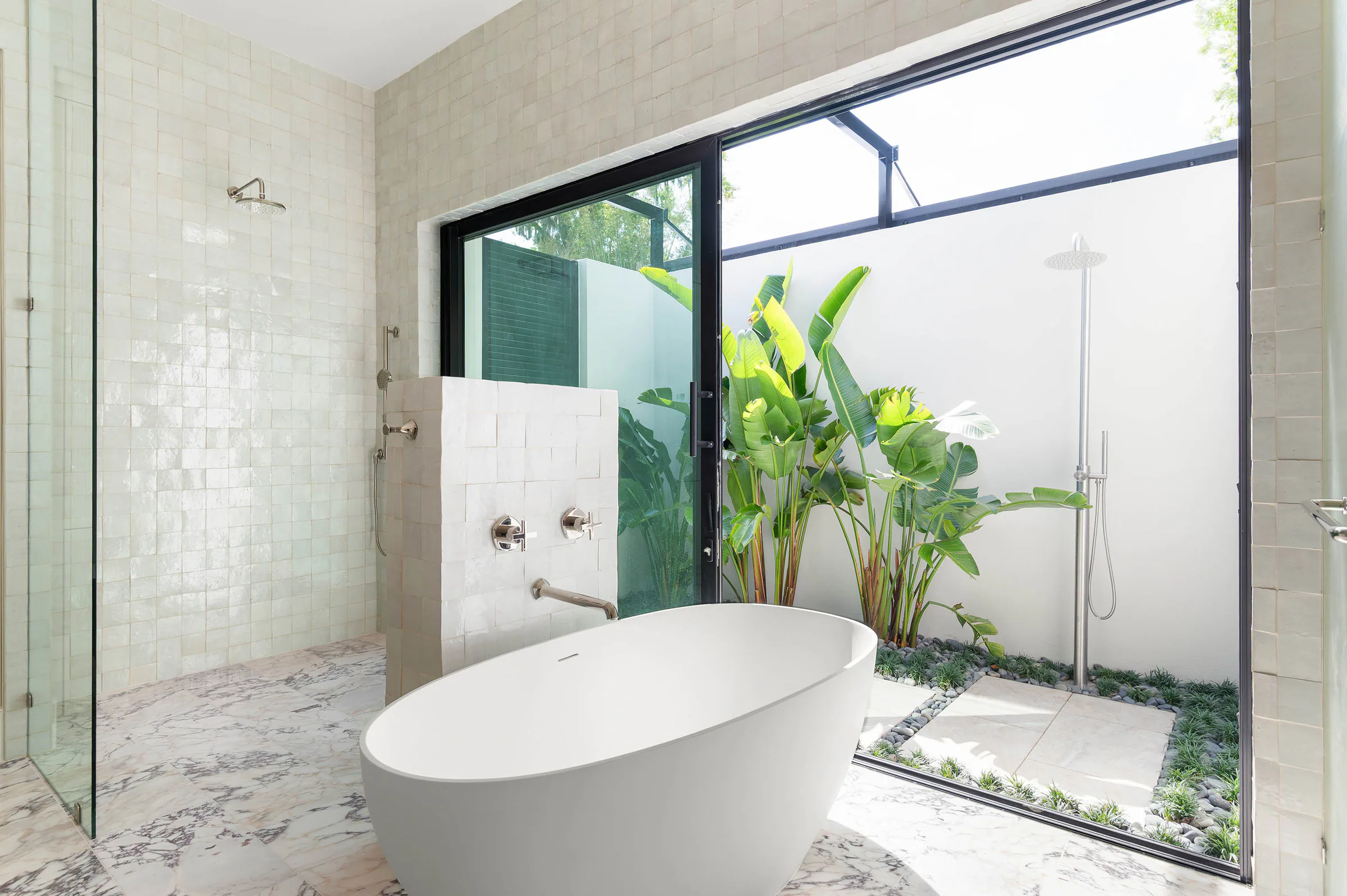 Freestanding tub and glass shower opening to a planted courtyard. Dana, a custom home by Rare Builders in Orlando.