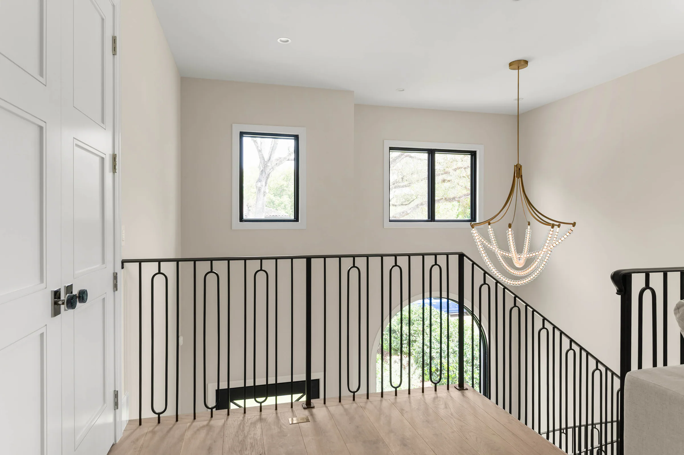 Upper landing with black metal railing and arched window.