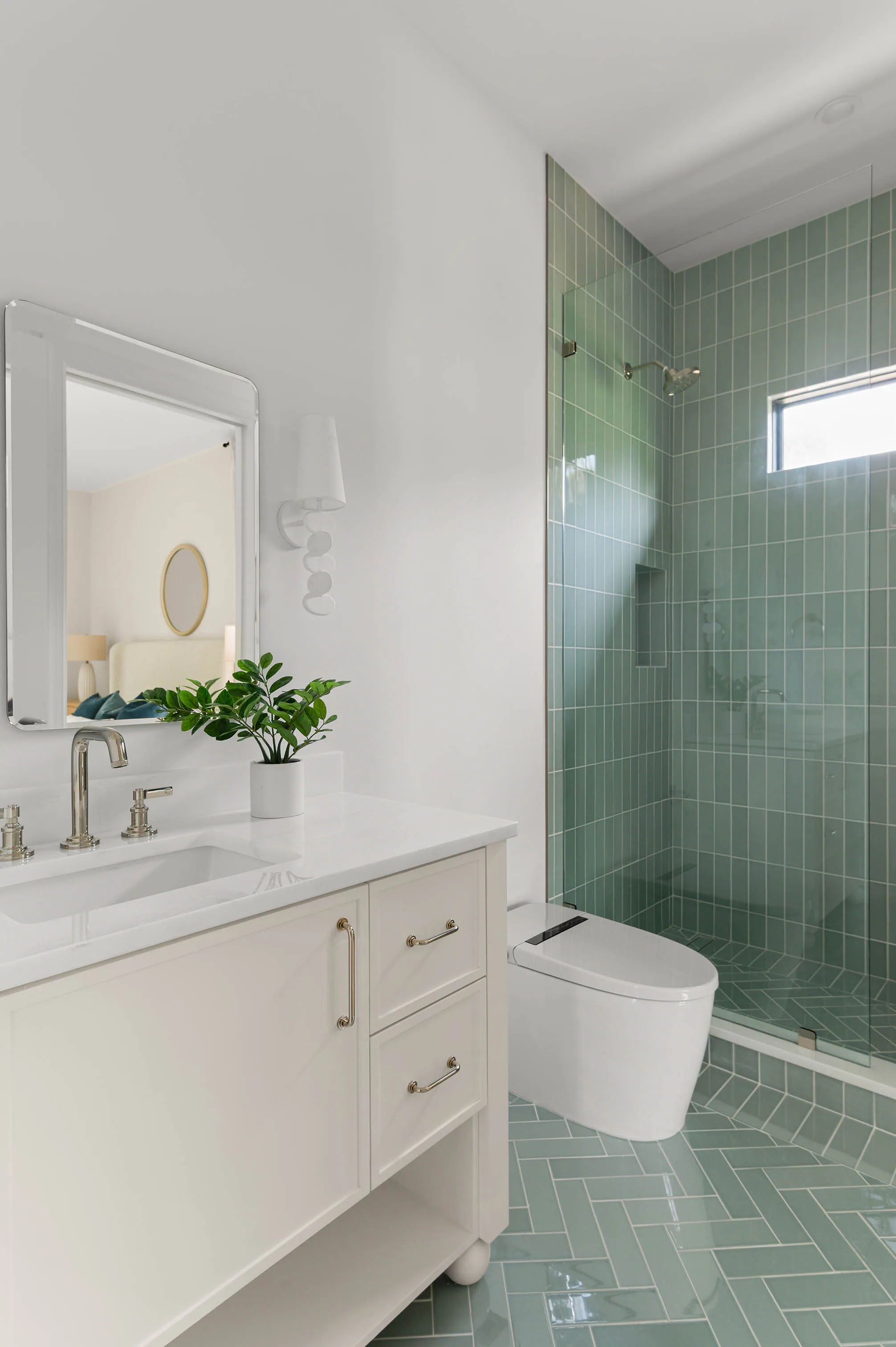 White vanity beside a deep green tiled shower.