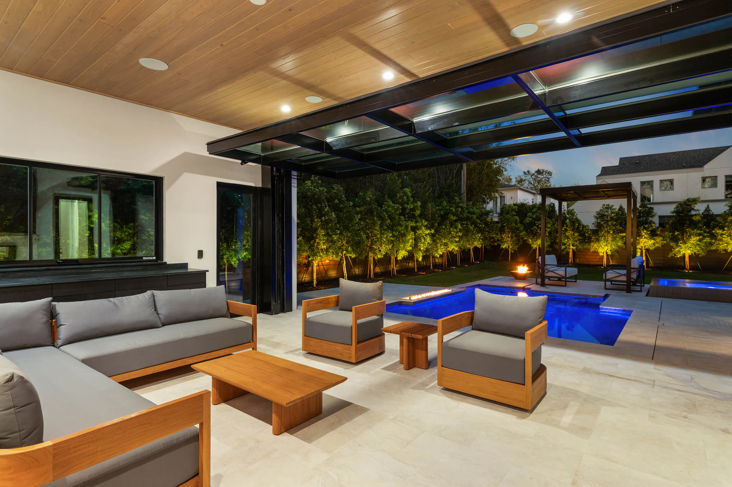 Covered outdoor lounge illuminated at night. Dana, a custom home by Rare Builders in Orlando.