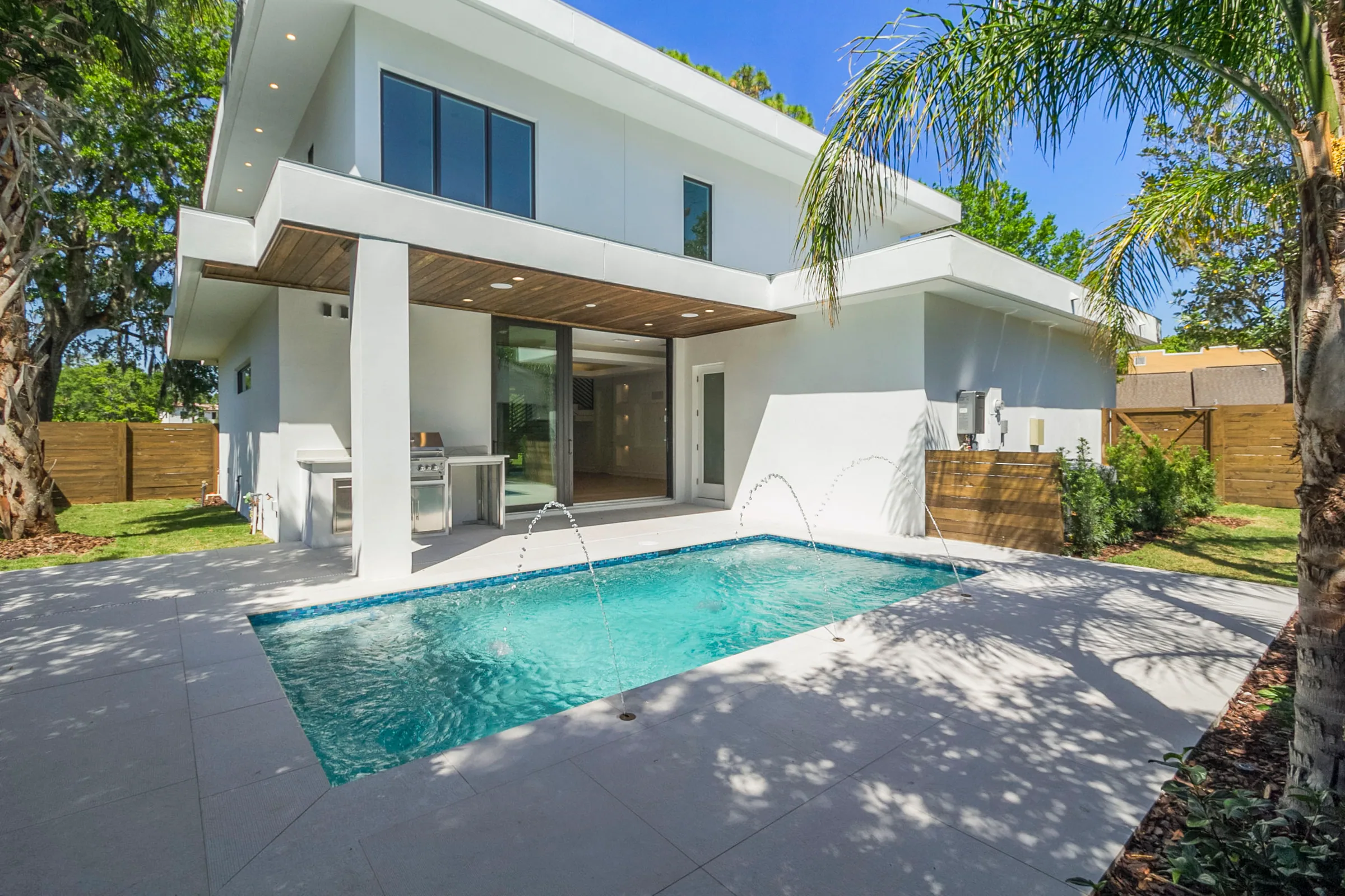 Wilbar rear elevation with broad overhangs, glazed doors, a covered terrace and rectangular pool.