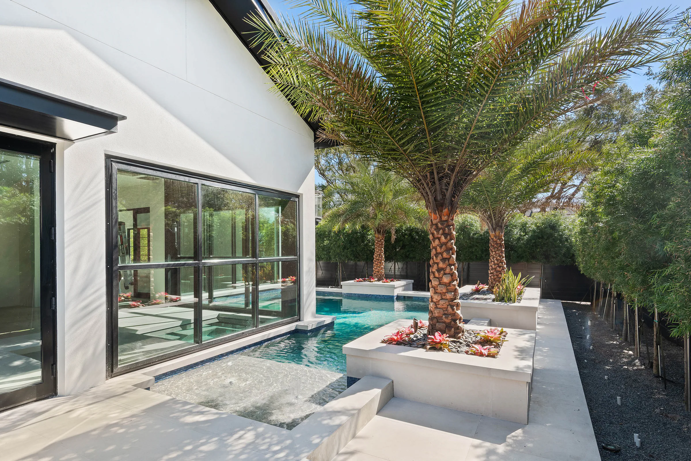 Pool and spa framed by palms and white rear pavilions. Oakwood, a custom home by Rare Builders in Orlando.